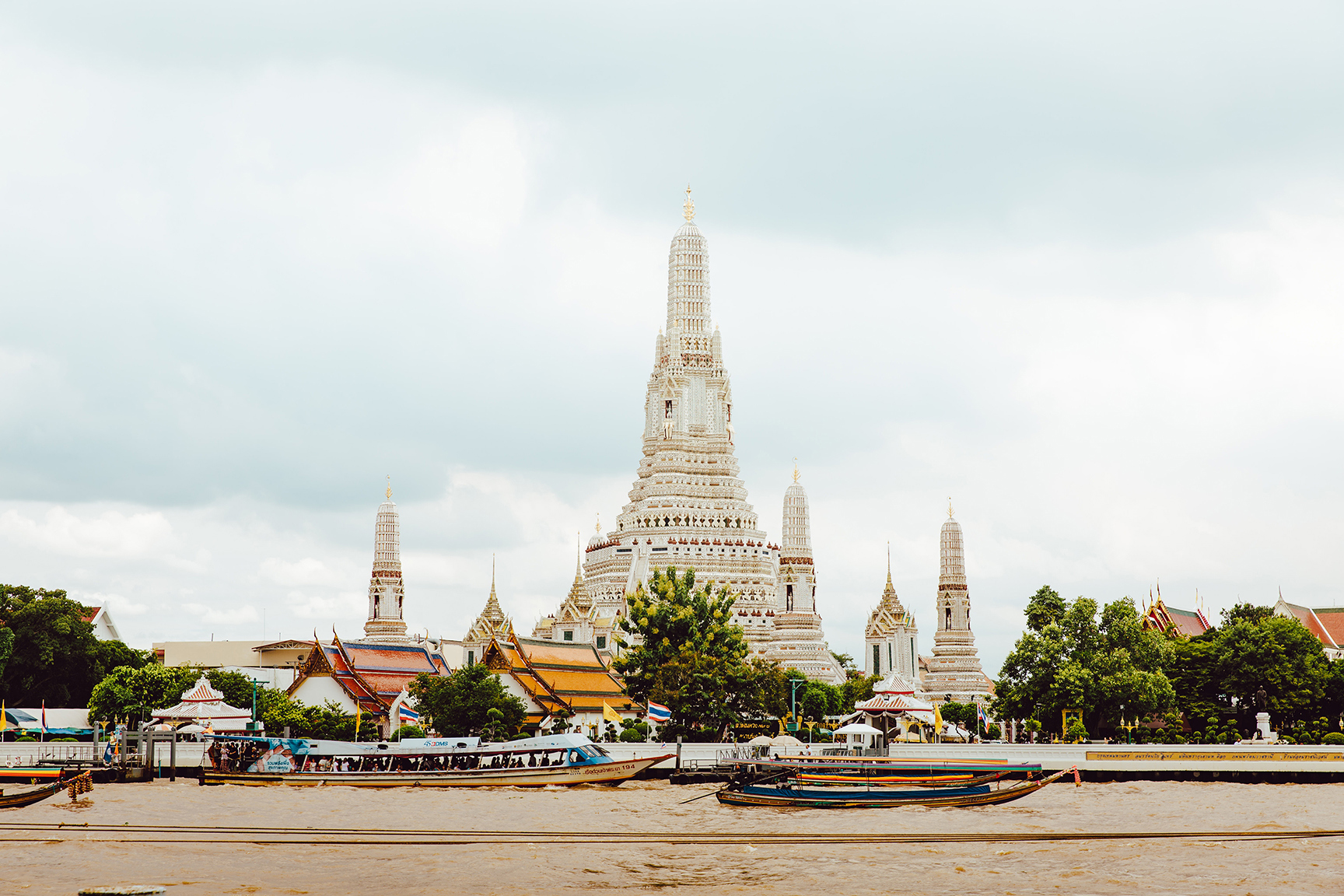 View of Wat Arun Ratchawararam Ratchawaramahawihan in Bangkok from across the river with boats passing