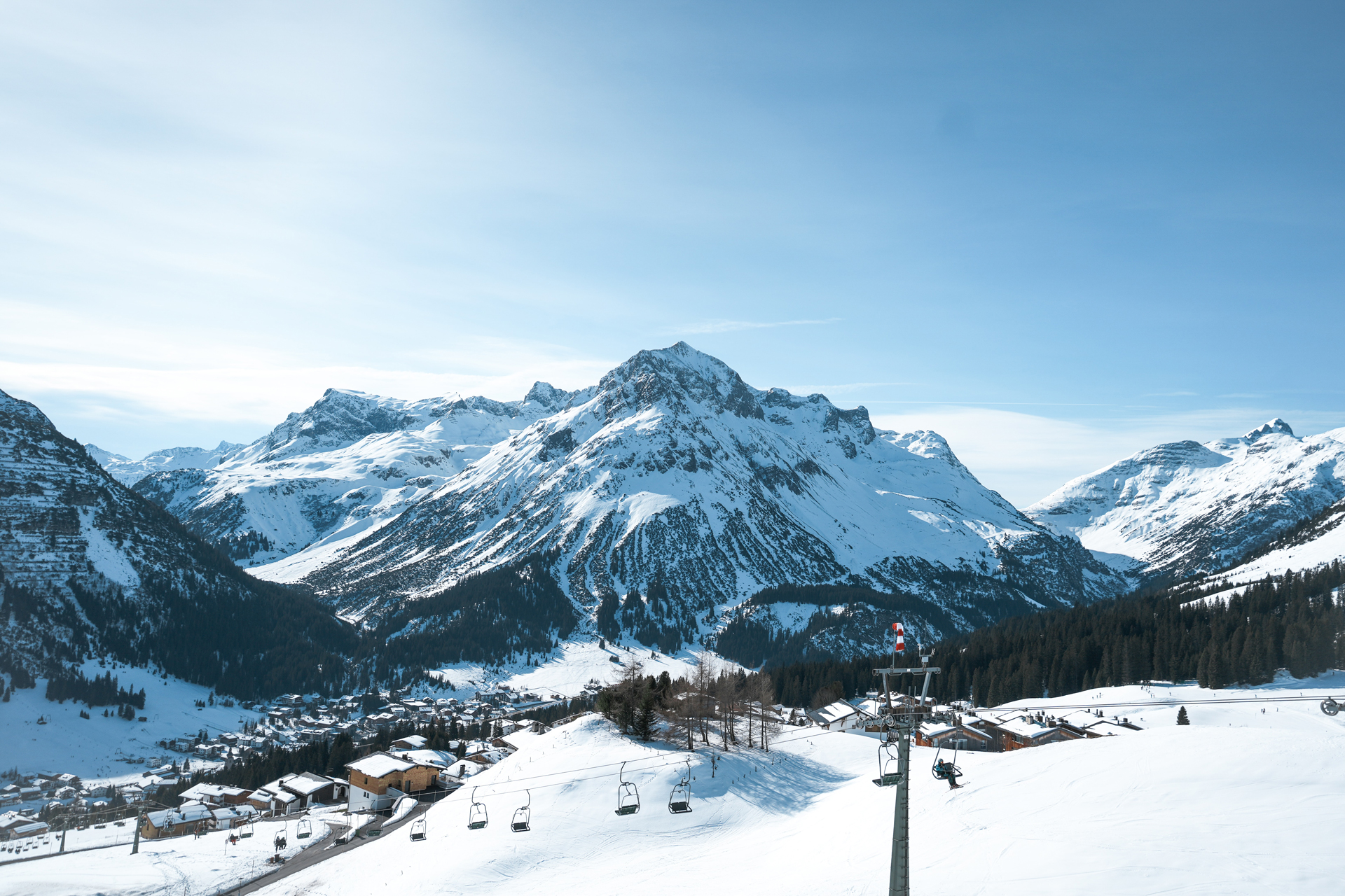 A ski lift and village seen in the valley bellow mountains