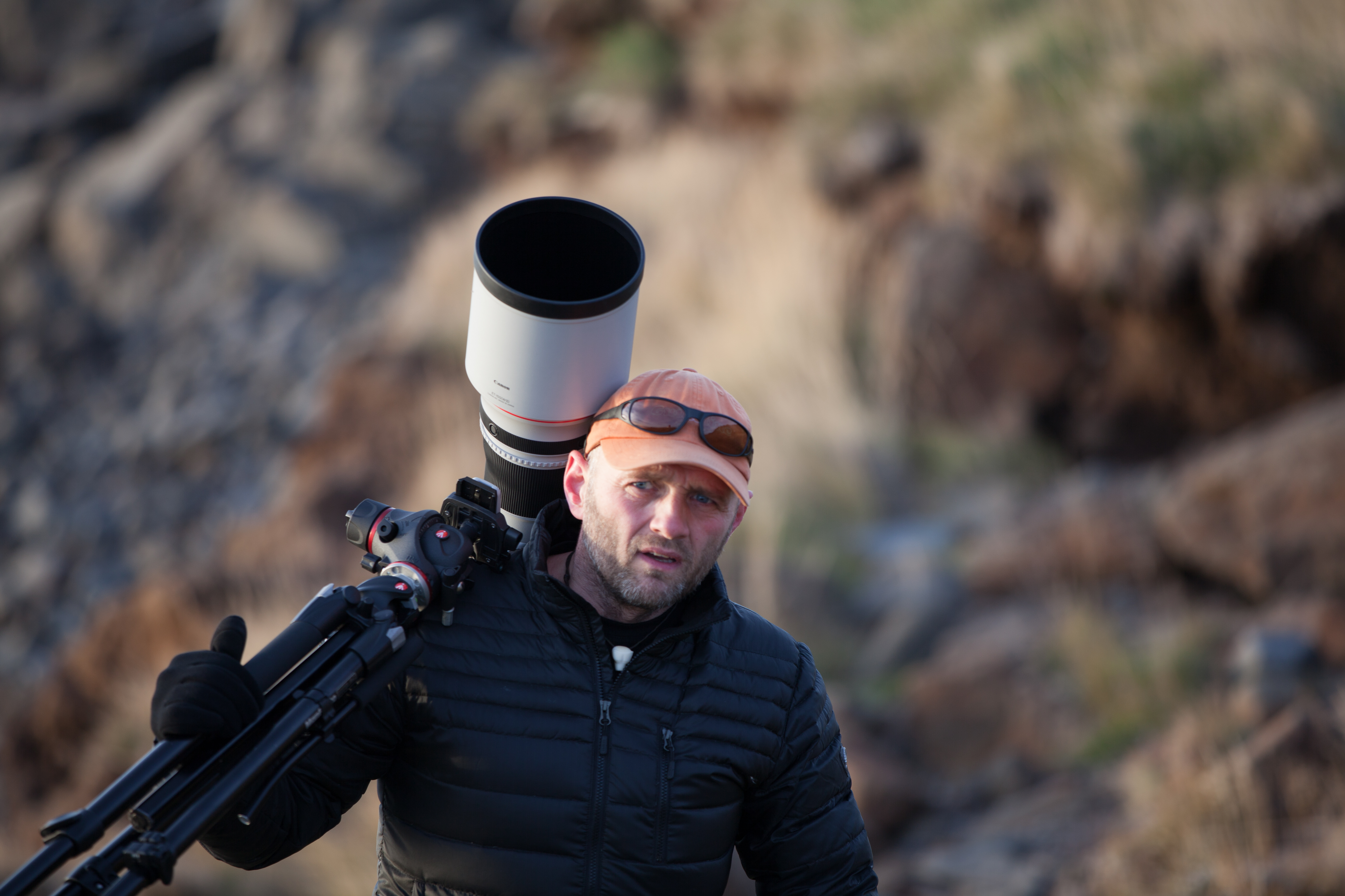 A man carrying a big camera on a tripod
