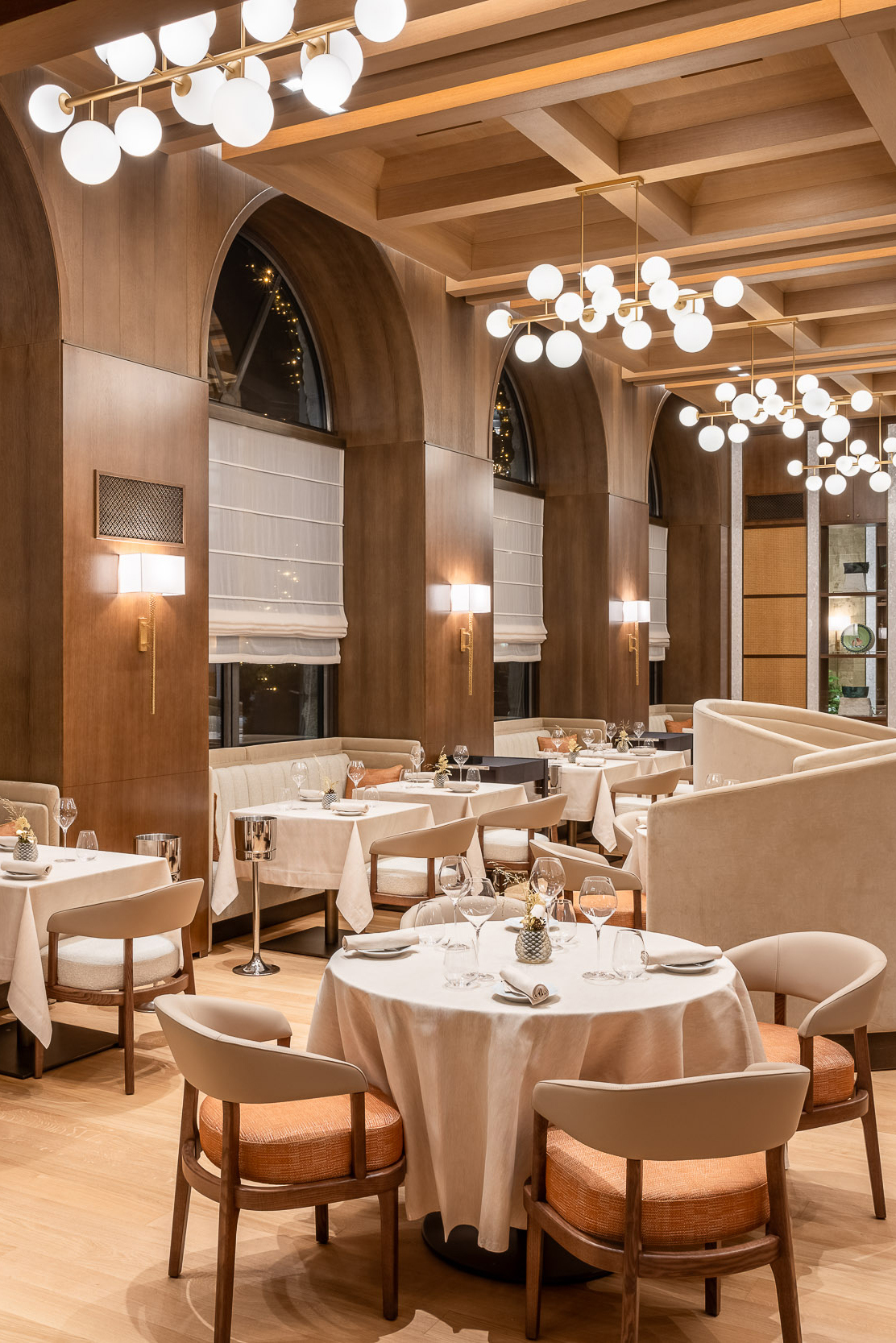 The stylish 1224 Restaurant at Grand Hotel Savoia featuring elegant tables set for dinner beneath statement bubble lighting and beamed ceilings