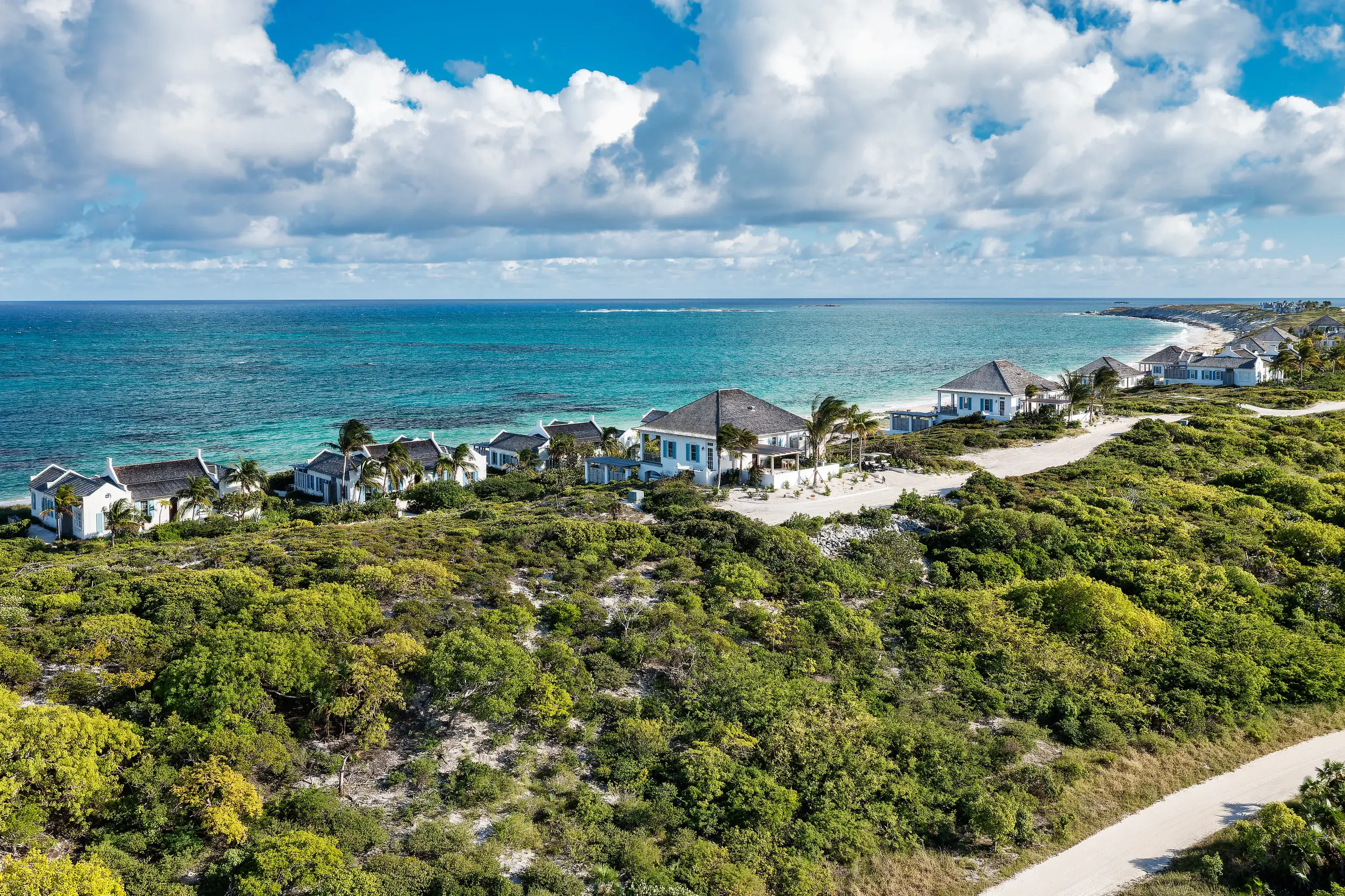 Aerial view of the beach villas at Ambergris Cay in Turks & Caicos lining the beach with the ocean in front and greenery behind