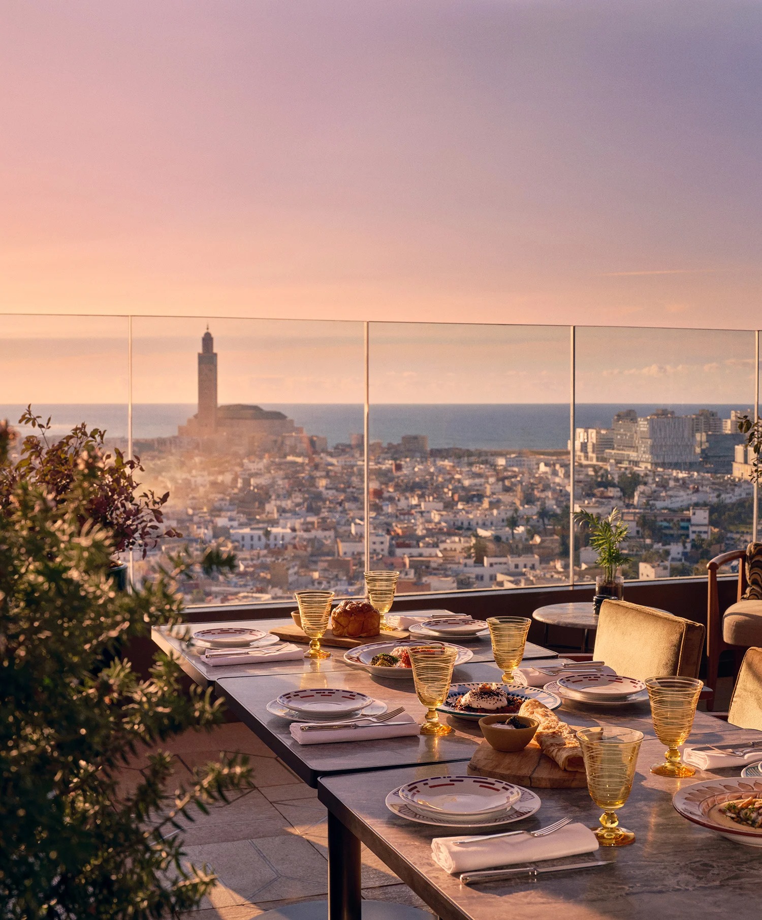 A table at Le Rooftop restaurant set for dinner at sunset with a view of Casablanca at golden hour