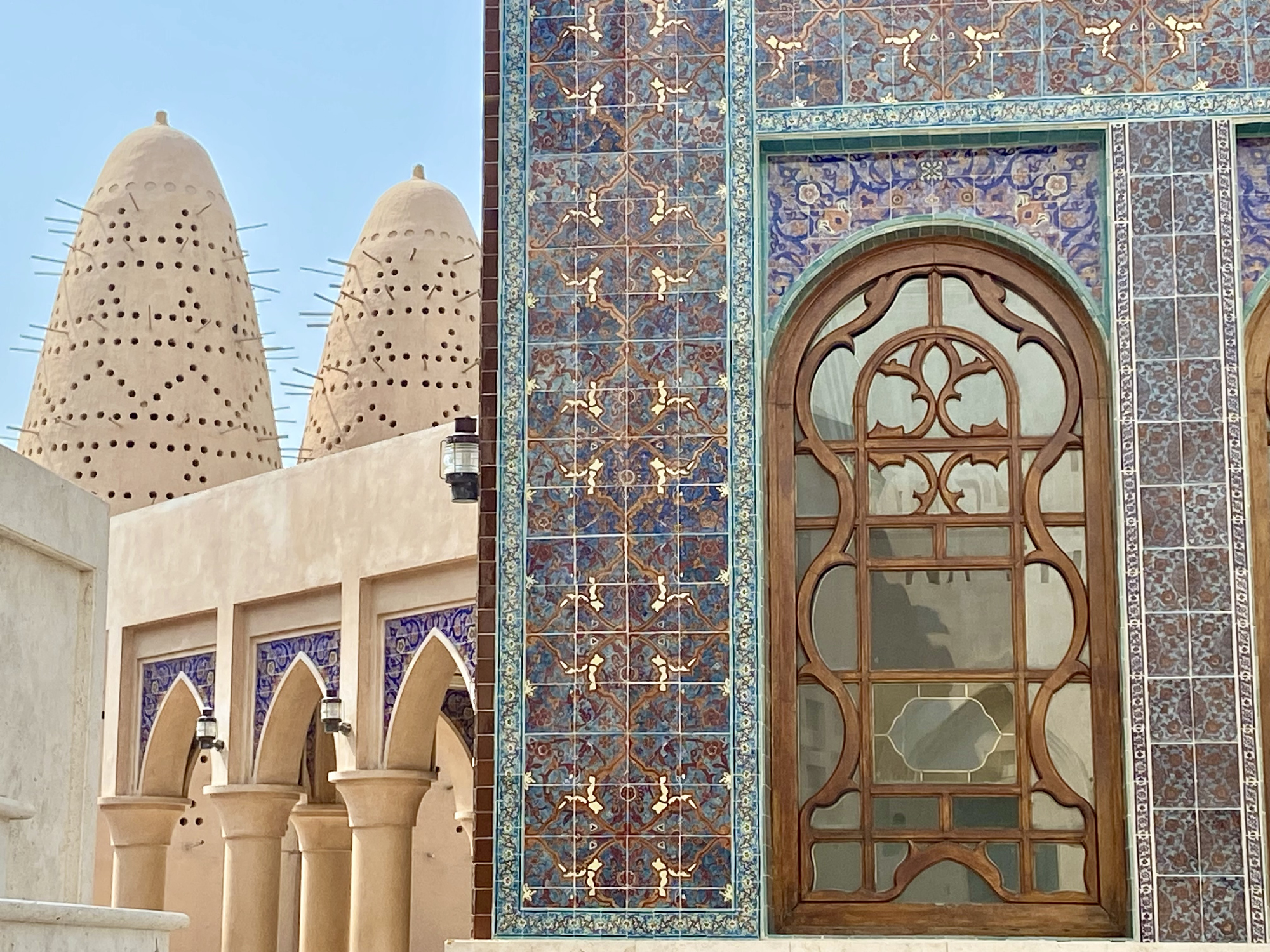 A section of a building with traditional Middle Eastern architecture, featuring ornate blue tile work and distinctive wind towers.