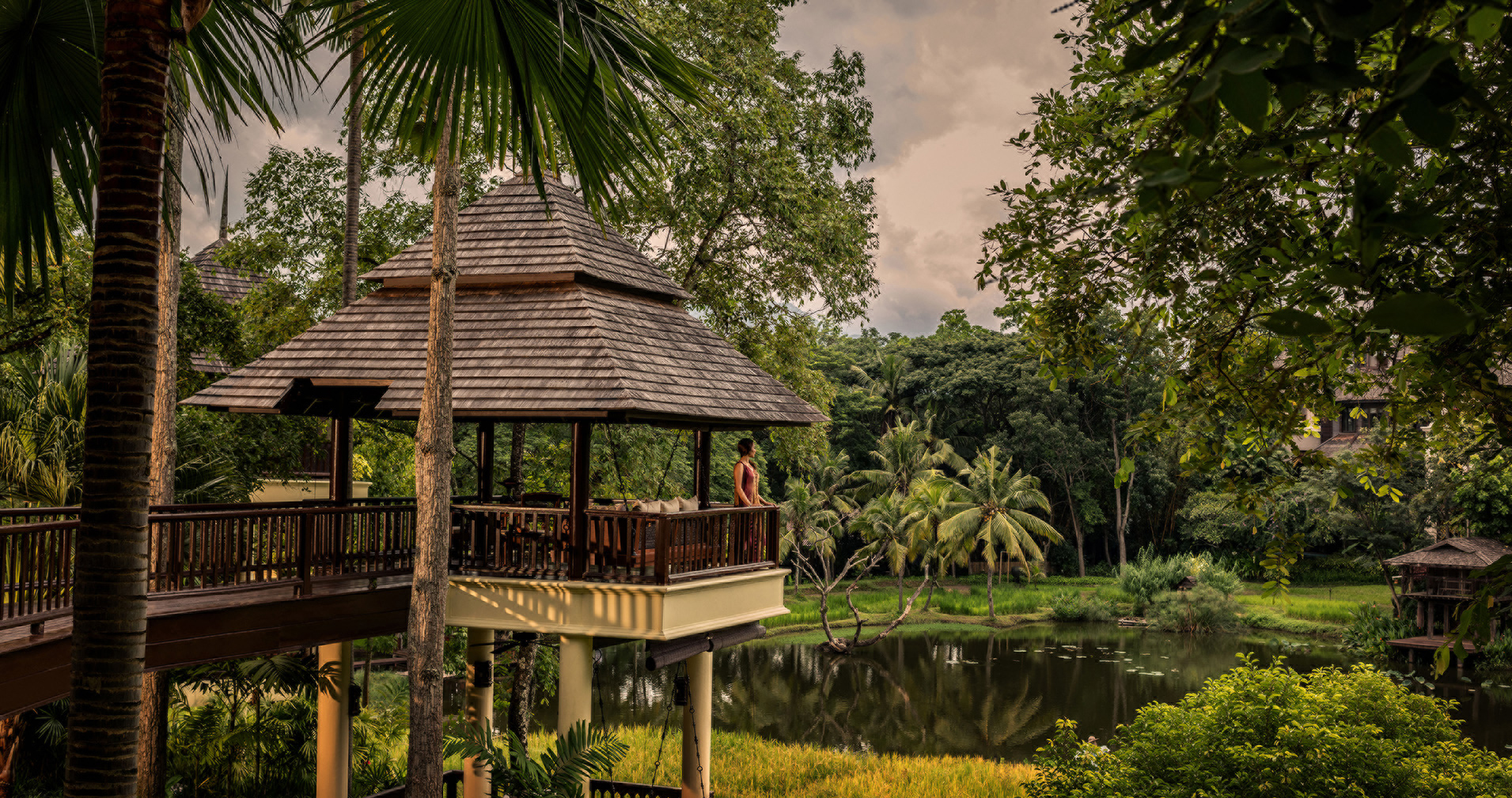 Asia, Thailand, Four Seasons Resort Chaing Mai, woman looking out at jungle and lake from a stilted pavilion