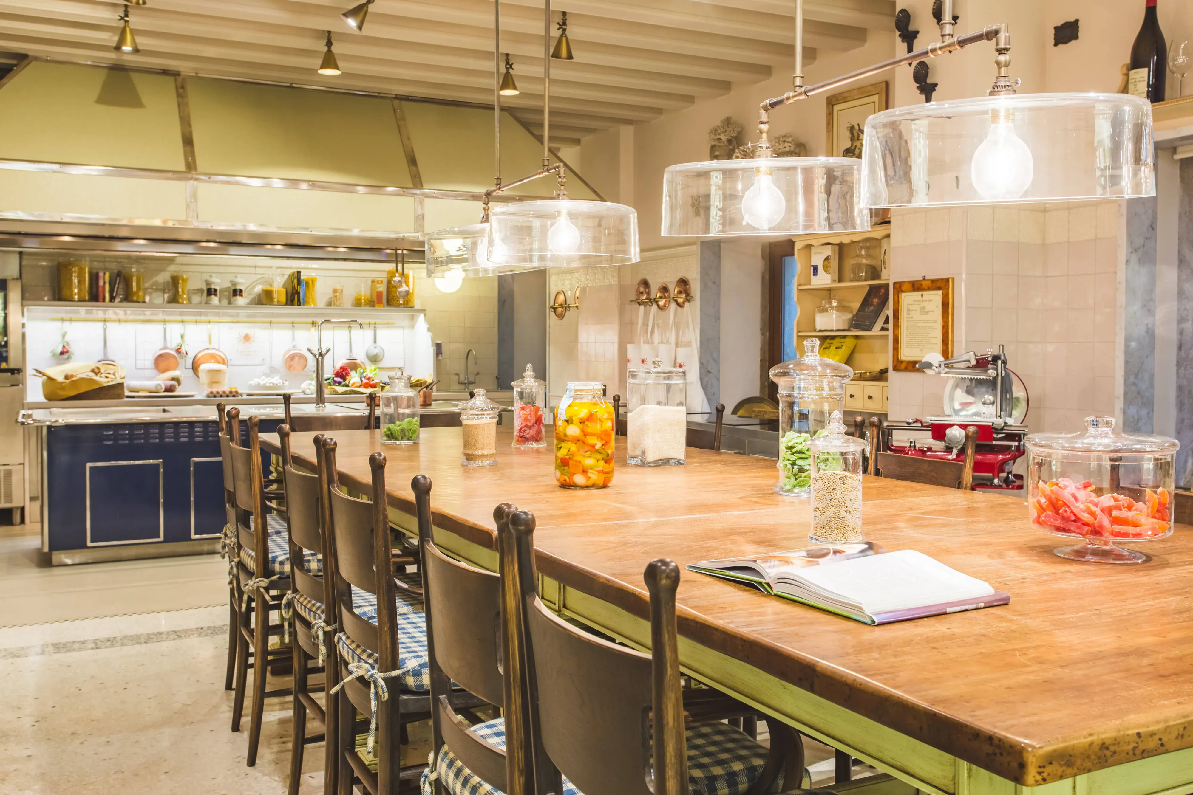 Rustic-style kitchen at The Gritti Palace in Venice featuring a large wooden island, hanging lights, and gourmet cooking setup.
