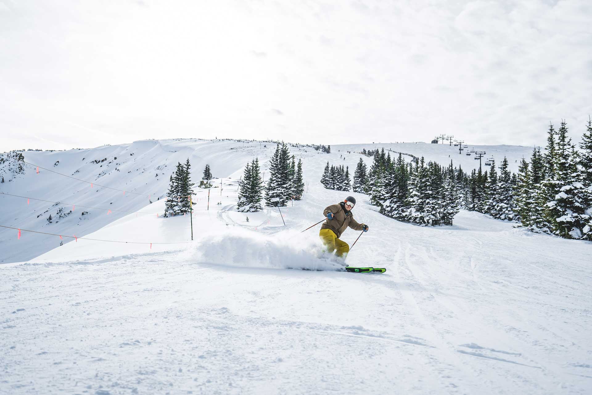 A skier turning before the camera and kicking up powdery snow