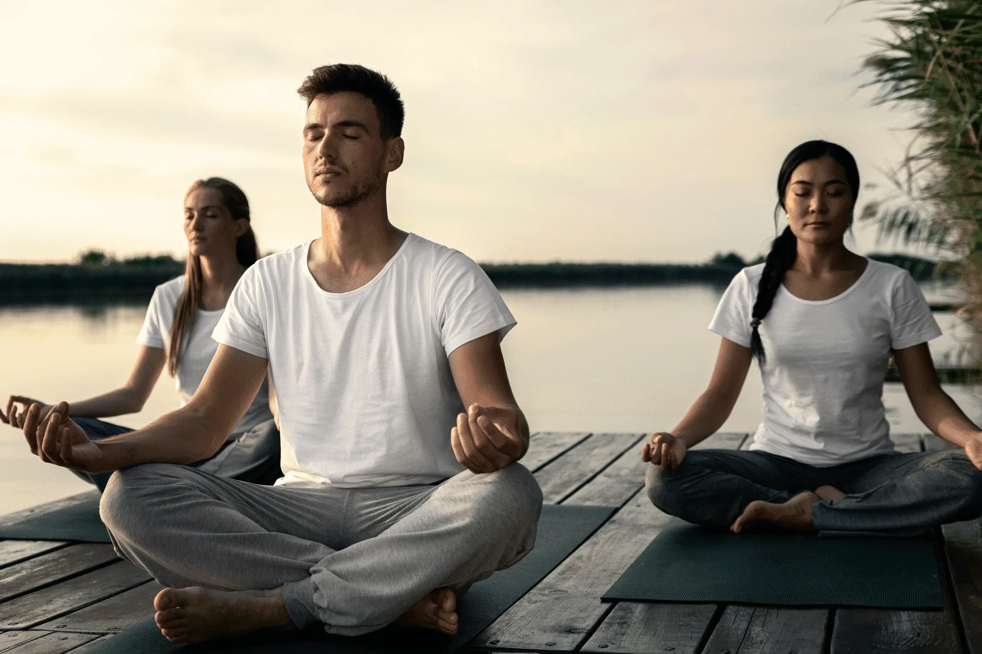 Guests meditating outdoors at Buff Medical Resort on a lakeside deck during calm, natural light.