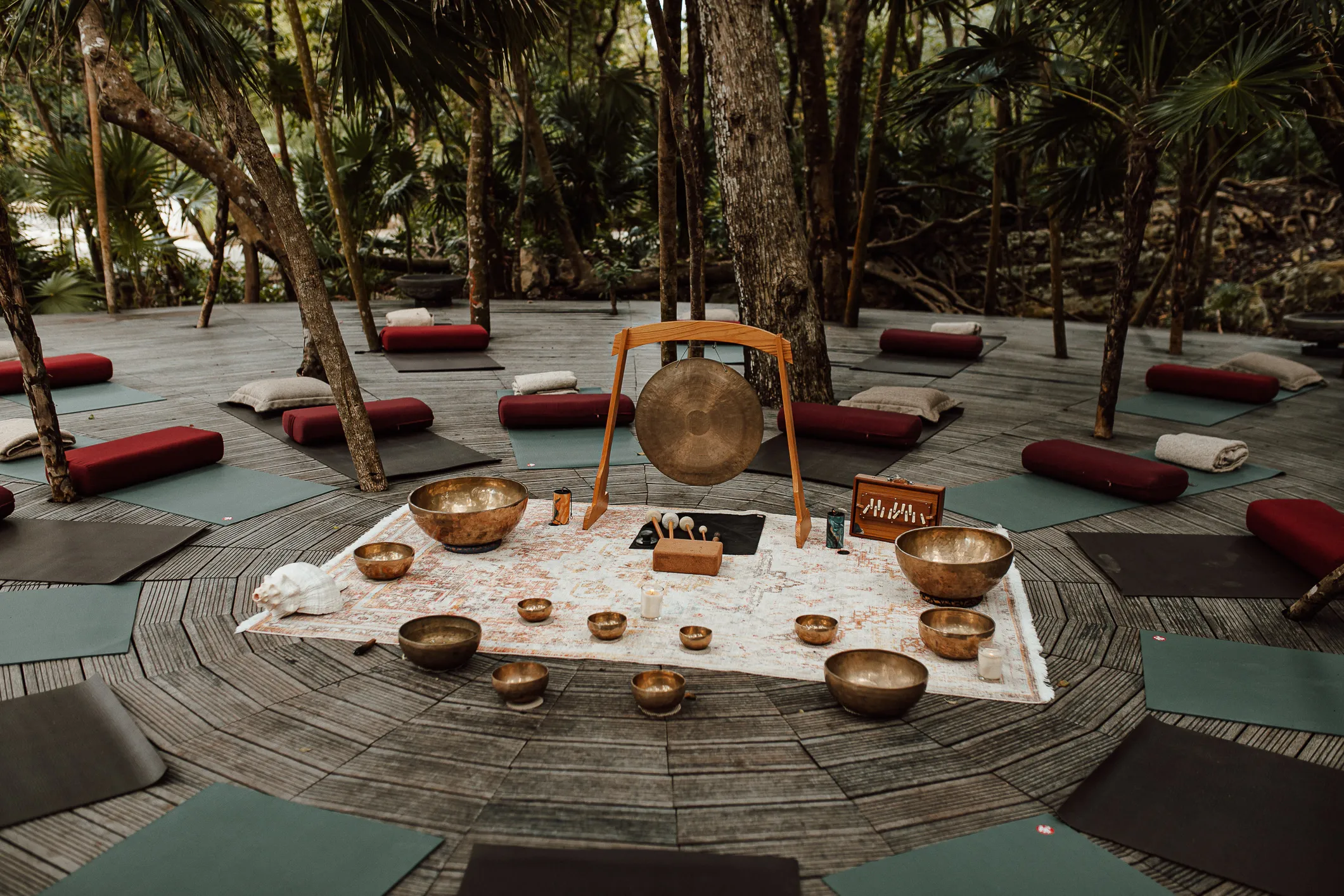Outdoor jungle deck set for yoga or meditation with mats, cushions and sound healing instruments.