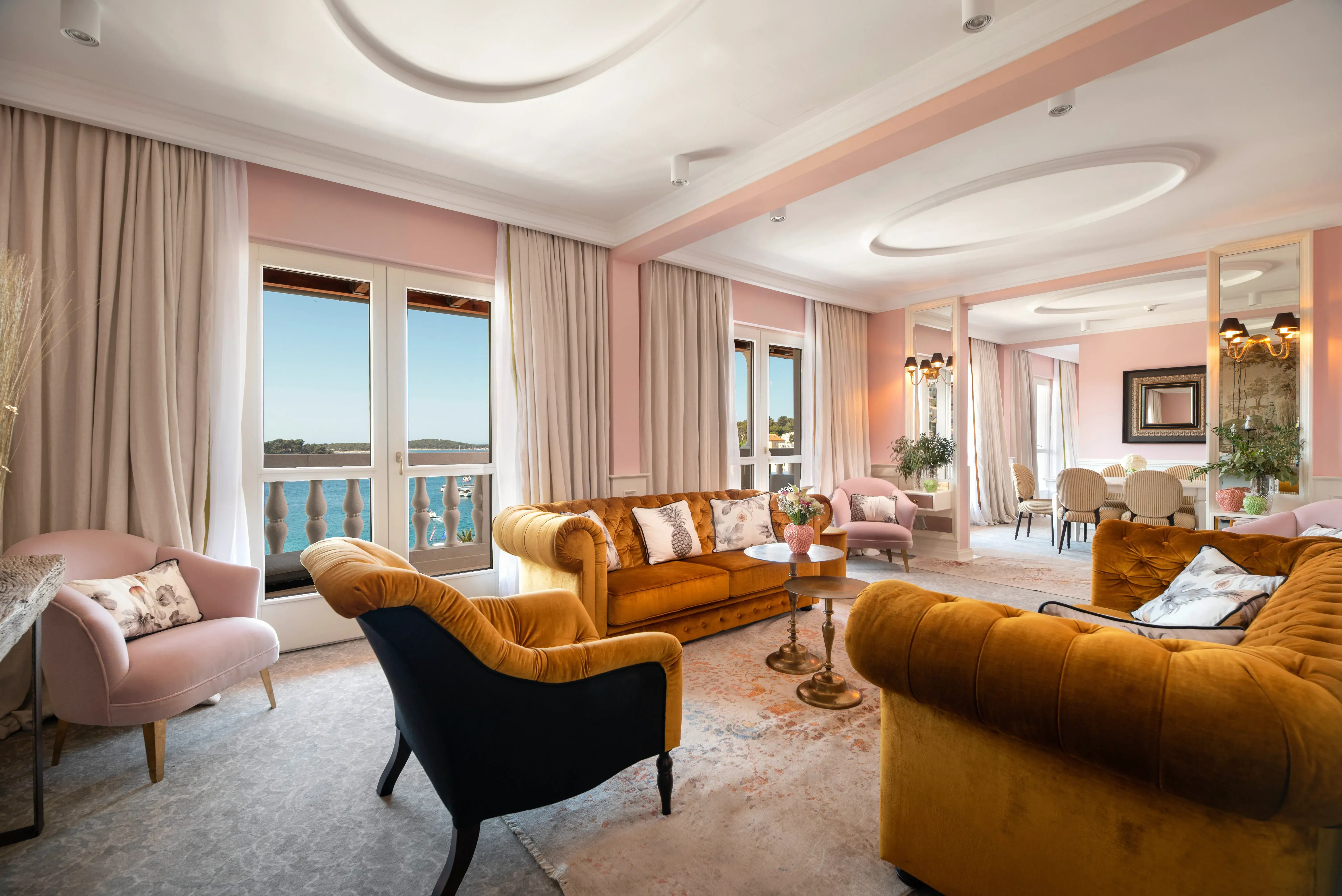 Lounge of a Presidential Penthouse Suite at Palace Elisabeth in Croatia featuring pink walls and gold furniture, with large balcony doors overlooking the sea