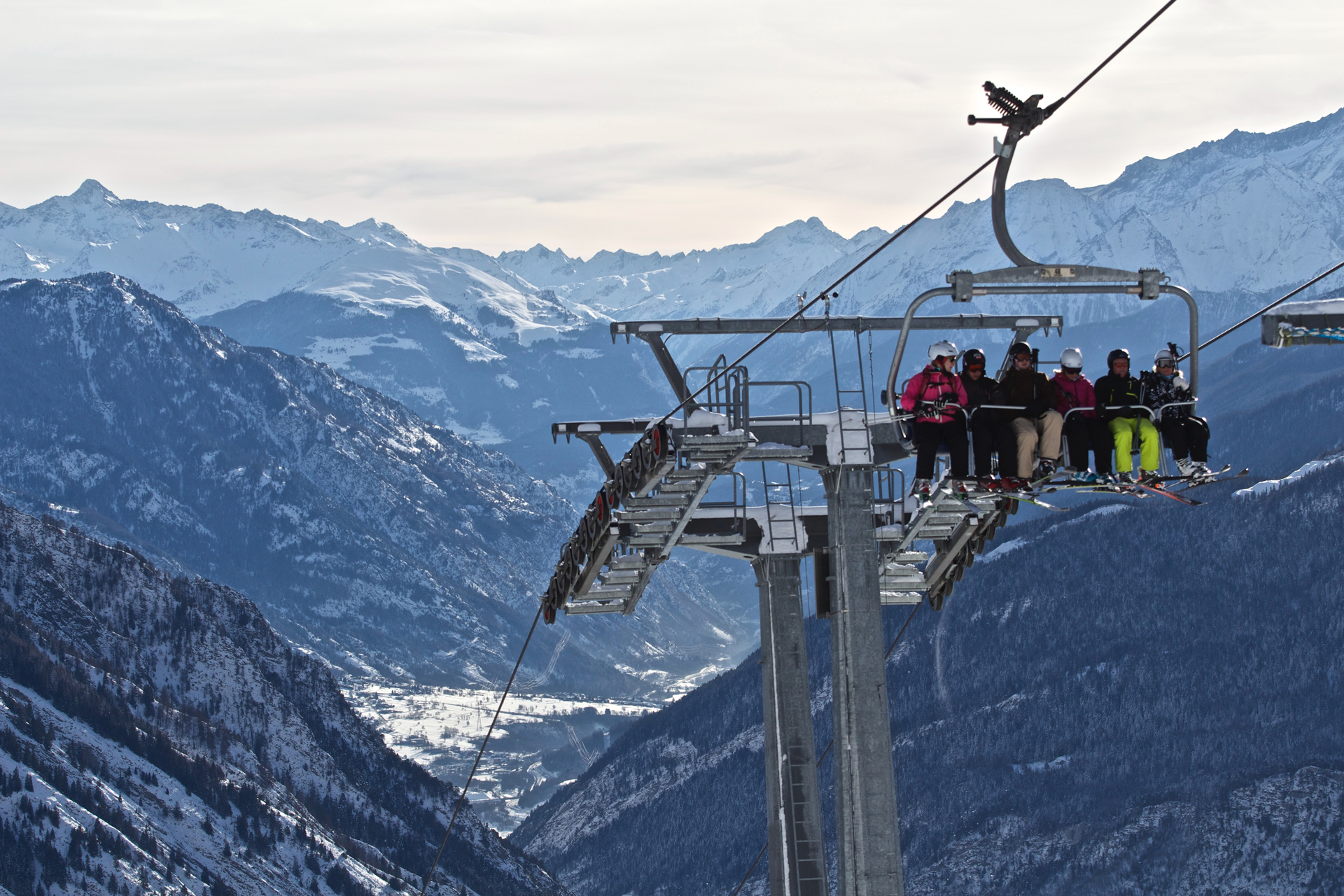 Ski lift filled with people with mountains in the background