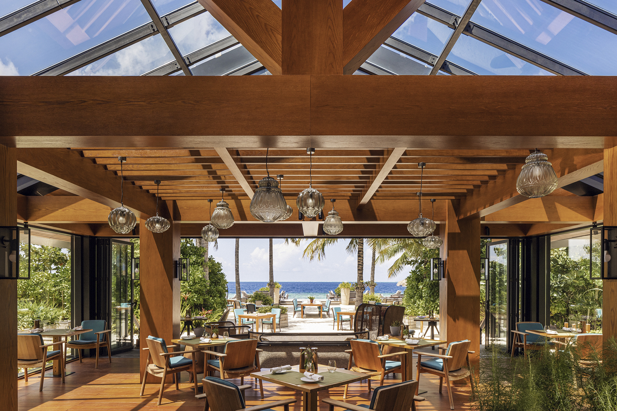 Glow Restaurant interior with tables set up for dinner and pendant lights hanging from wooden beams