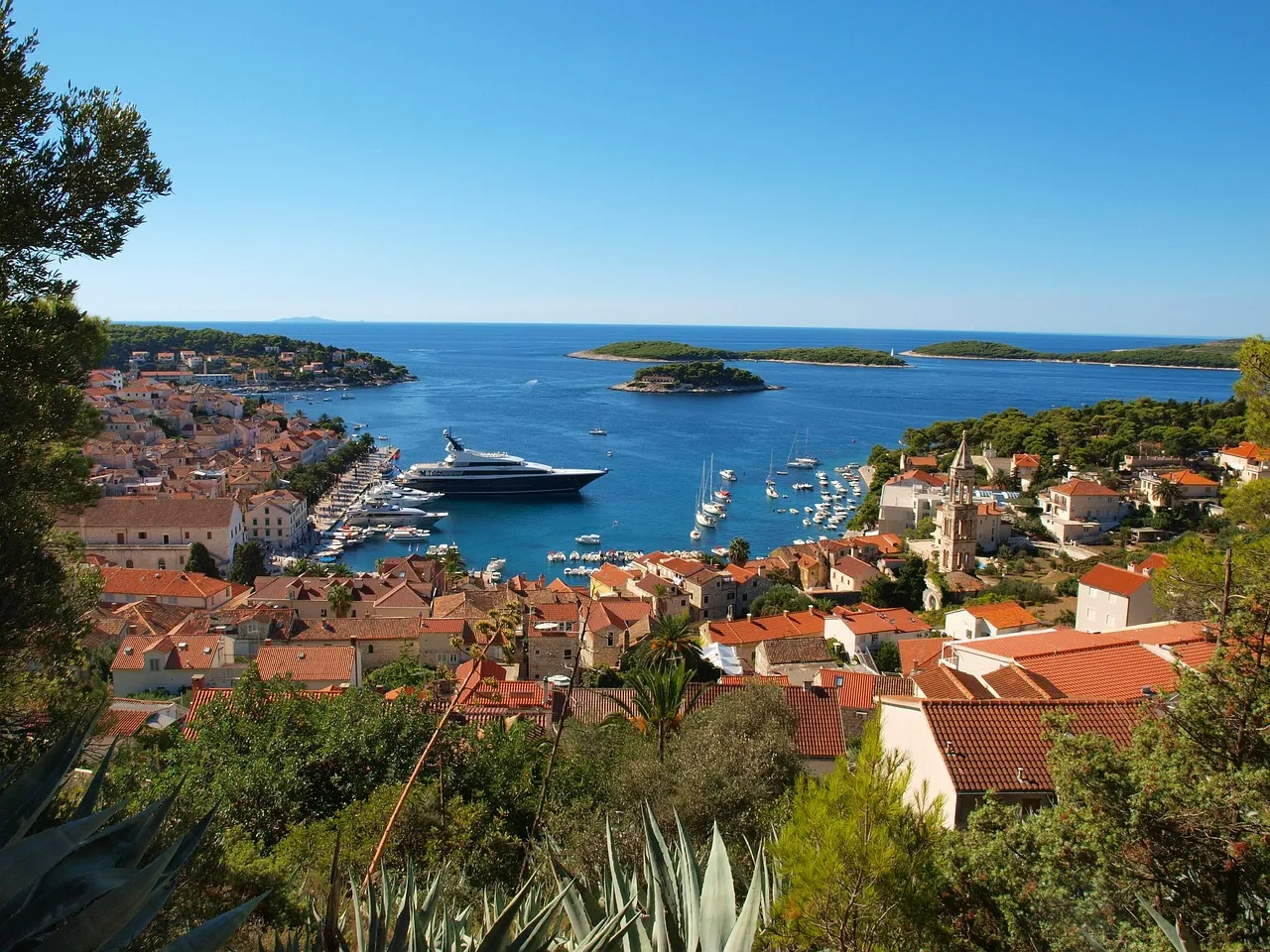 Elevated view of Hvar Town’s red-roofed buildings and harbor, with yachts and small islands in the Adriatic Sea.