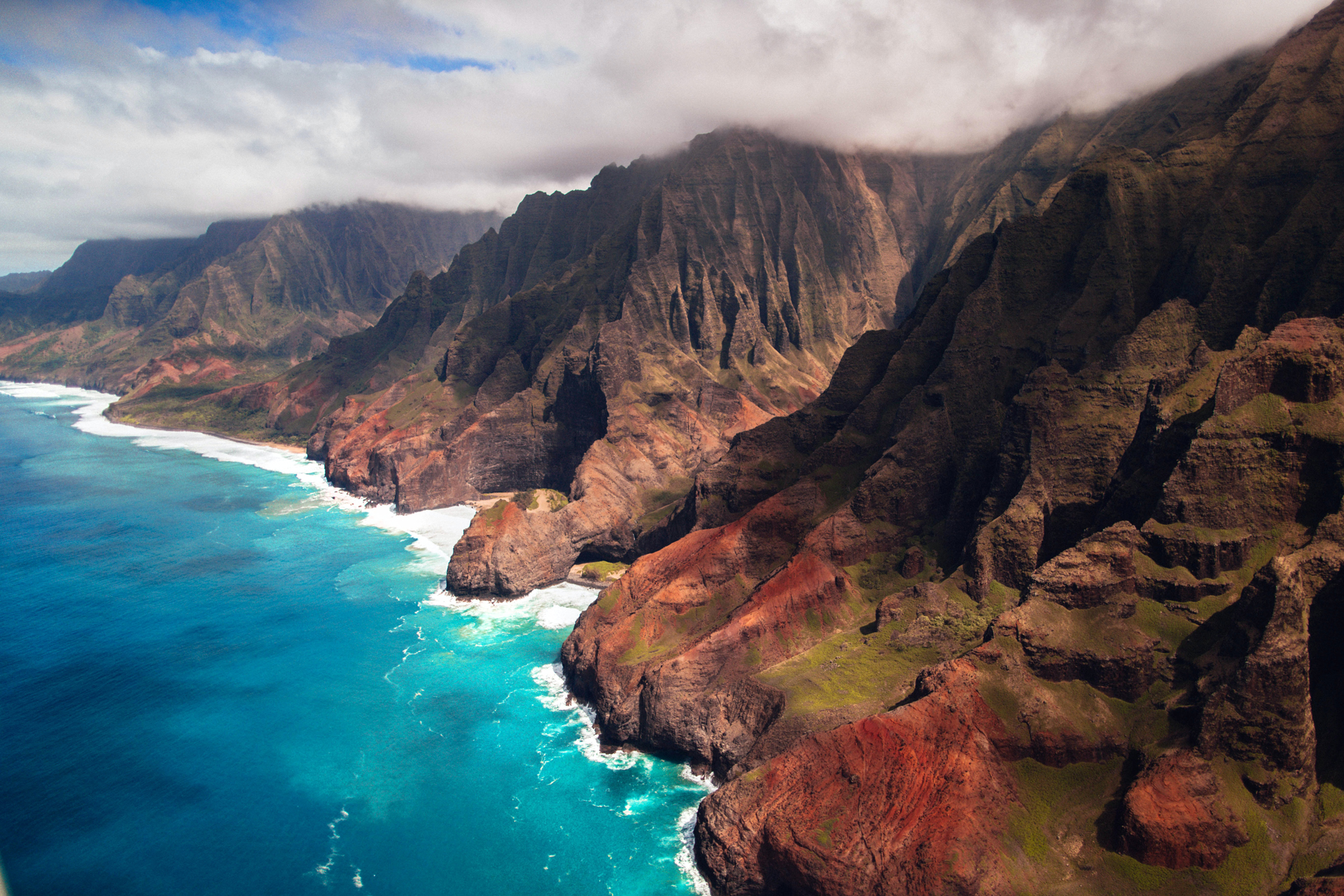 A picturesque landscape featuring a vividly colored ocean and tall green mountains