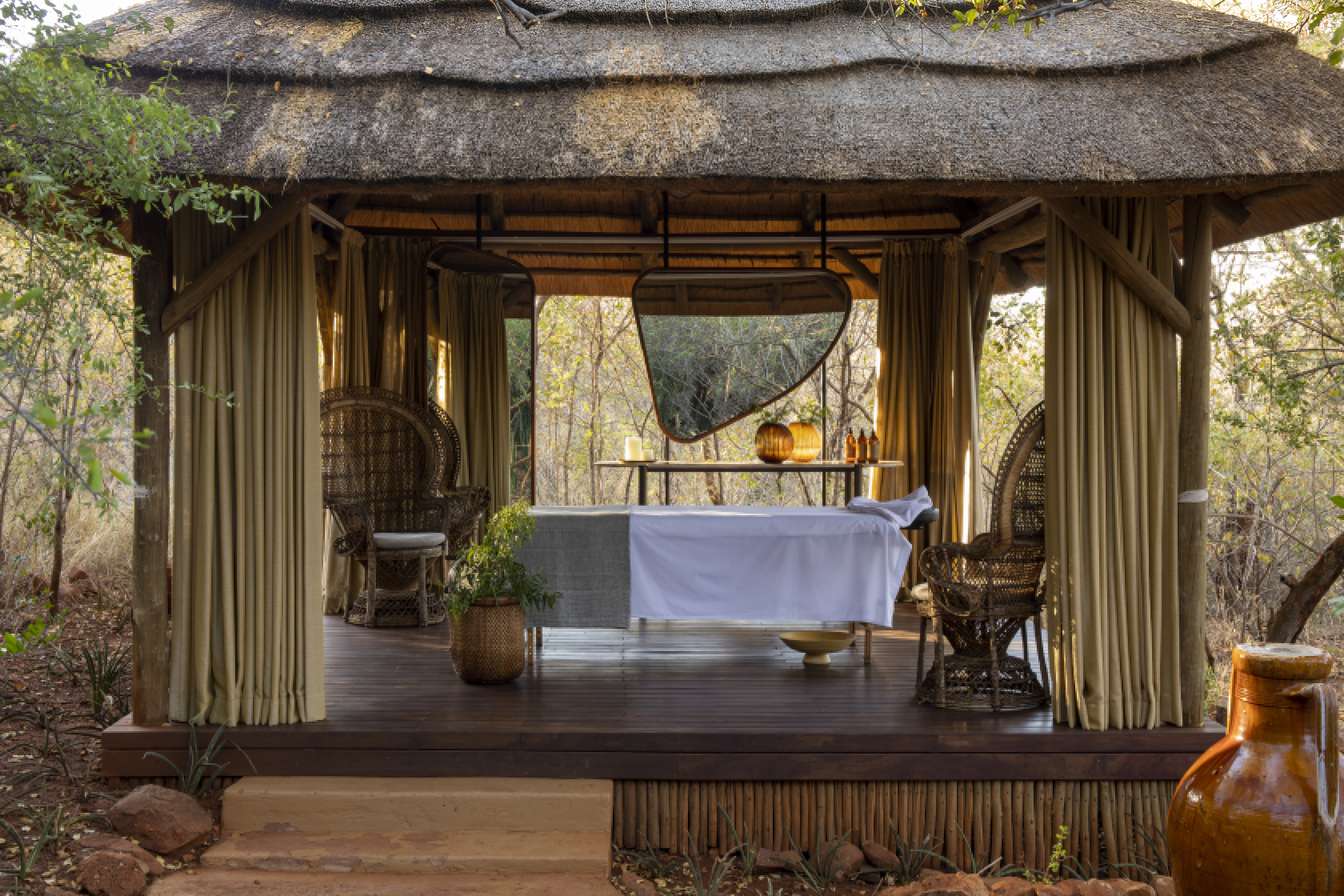 The spa deck of Molori Lodge featuring a thatched pavilion housing a massage bed and large chairs