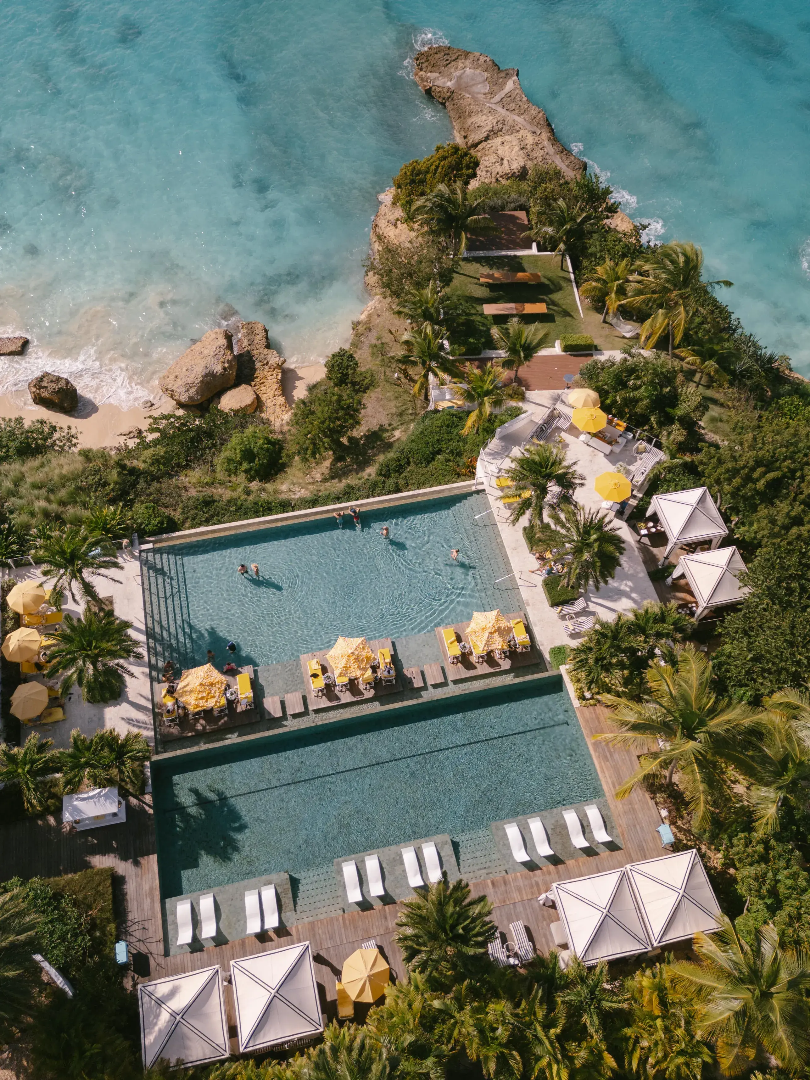 Aerial view of Malliouhana Resort’s infinity pool in Anguilla, overlooking turquoise Caribbean waters, tropical gardens, and dramatic coastal cliffs