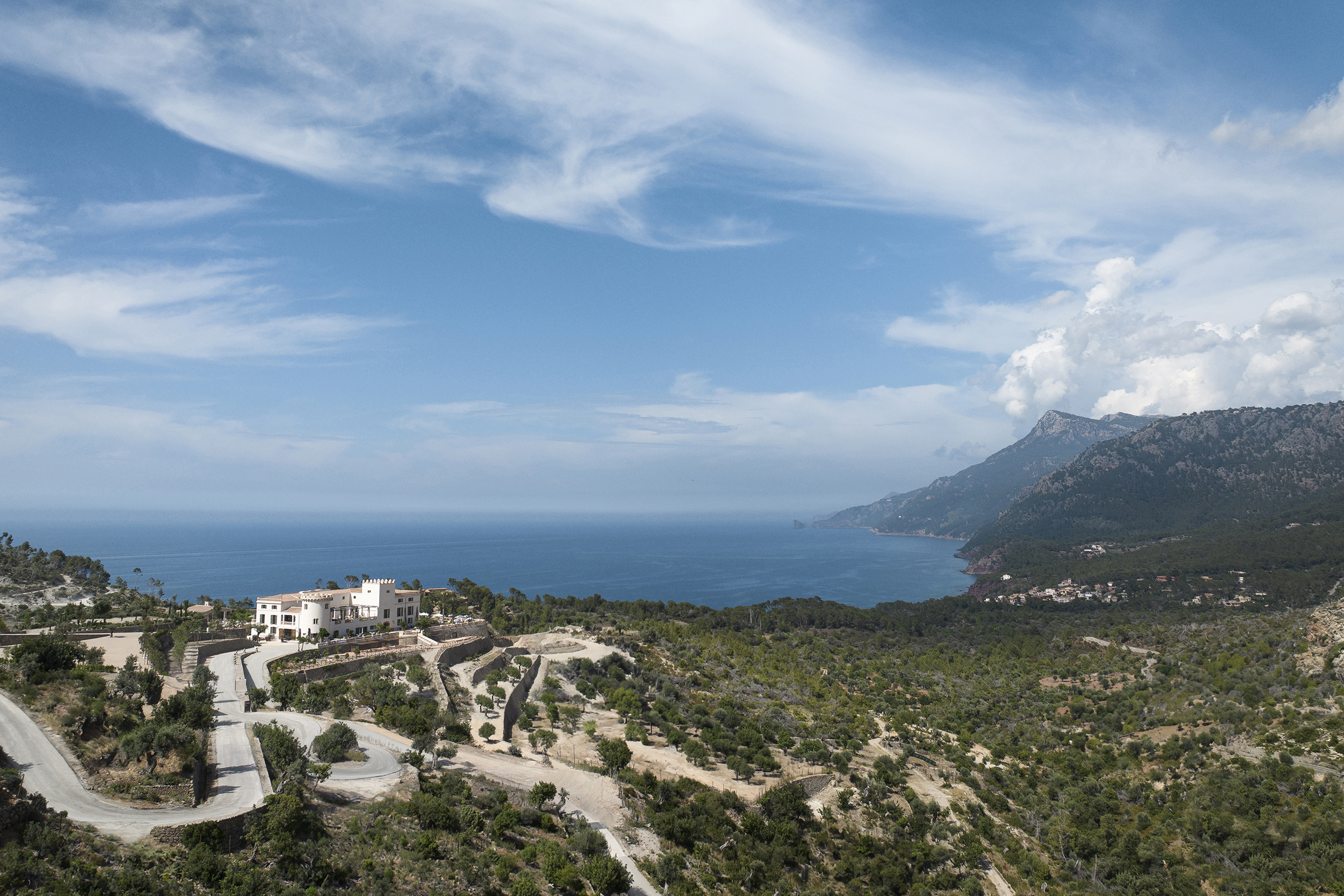 Mountains and ocean with whitewashed exterior of Son Bunyola in foreground