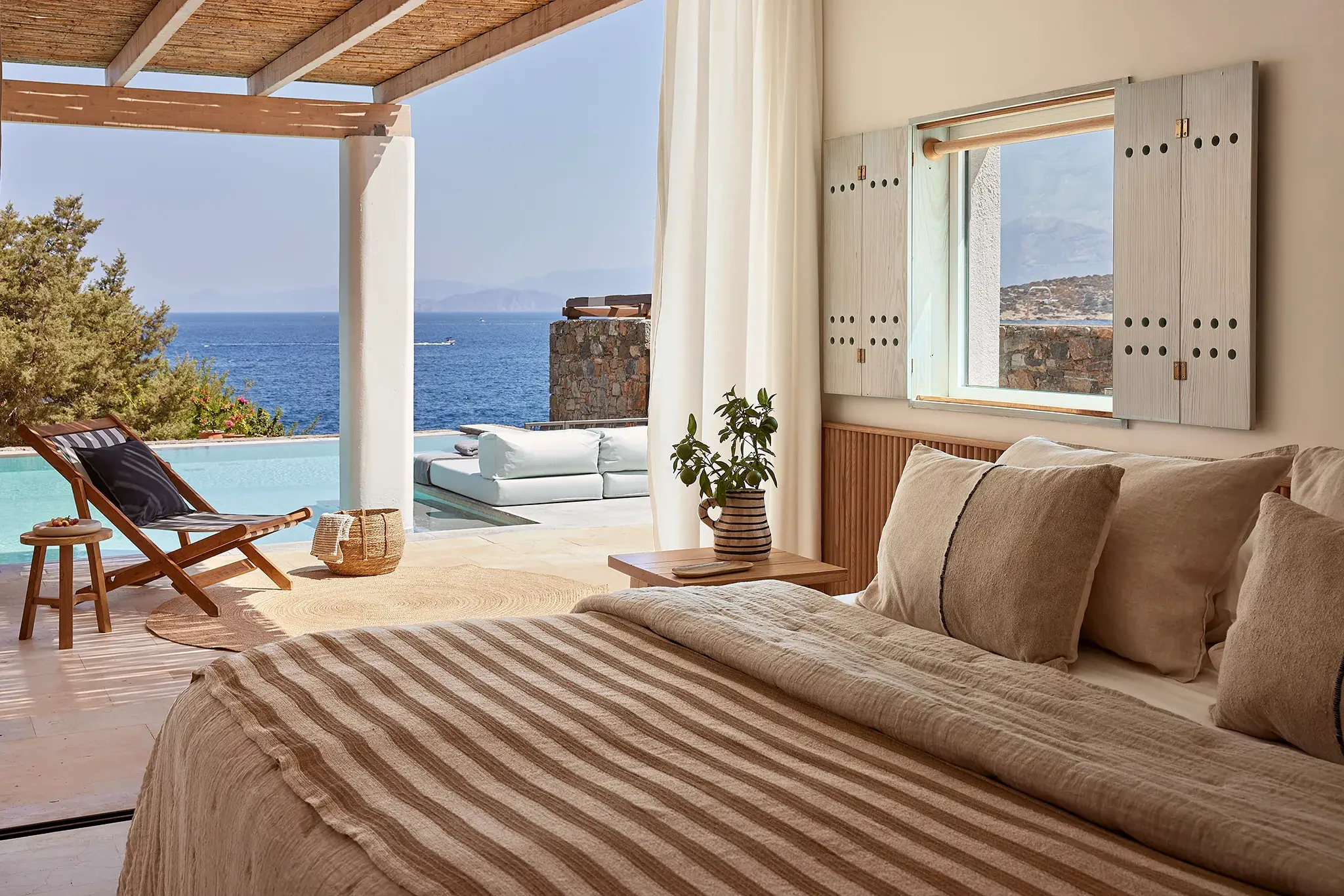 Luxury beachfront villa bedroom decorated in neutral tones with sea view and private terrace at St Nicolas Bay, Crete.