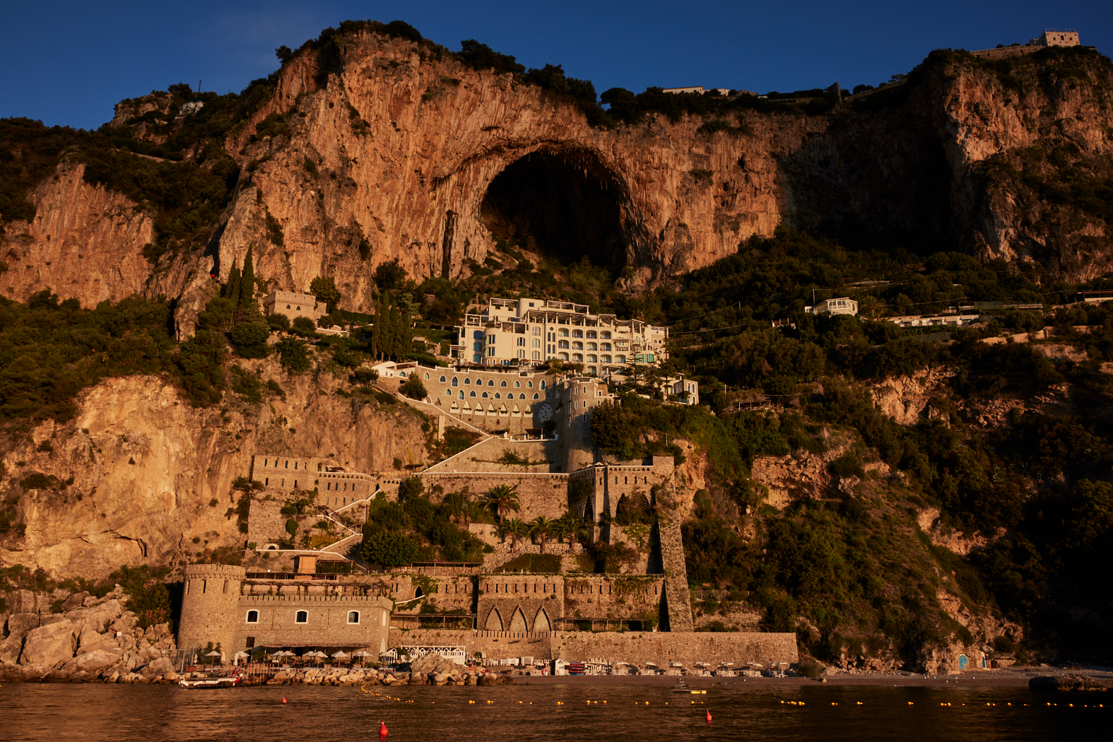 Breathtaking sunset view of Borgo Santandrea in Amalfi with luxurious cliffside architecture and dramatic rocky landscape.