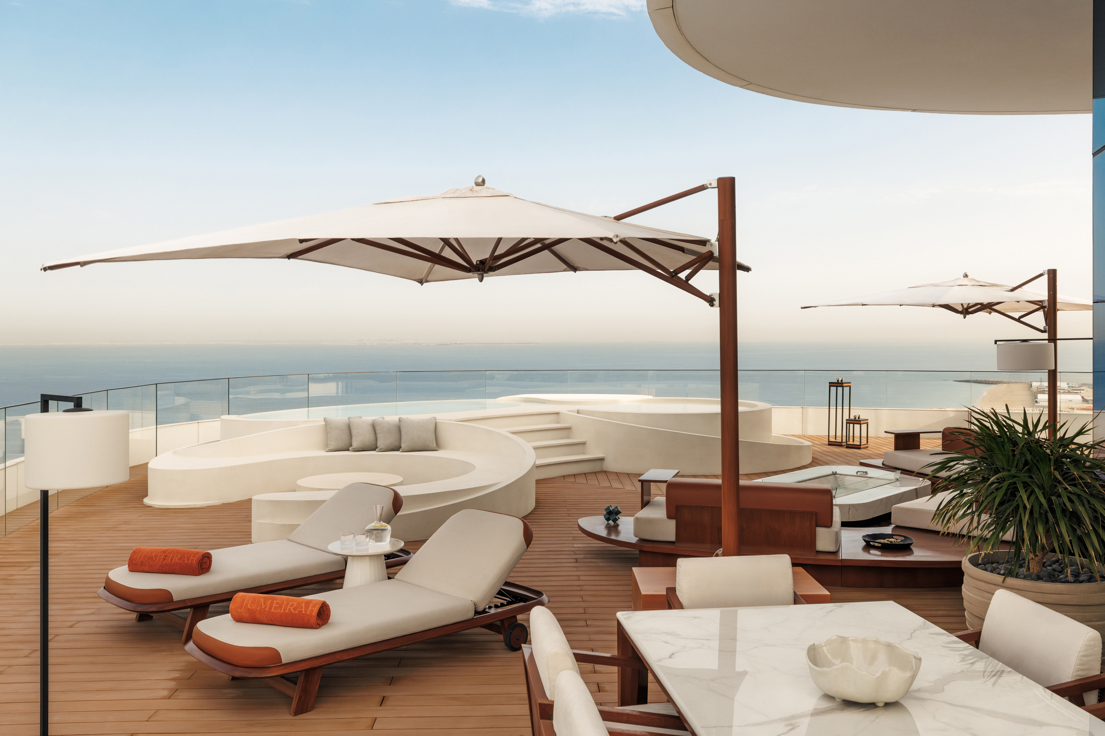 A large terrace with cream furniture and a plunge pool with a view of the ocean
