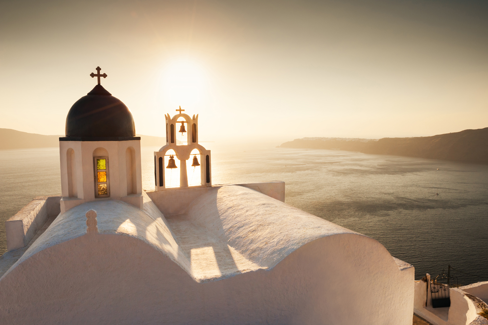 White church with a bell tower on the sea coast at sunset