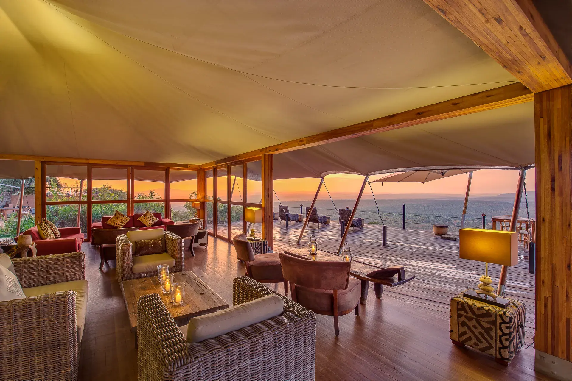 The communal lounge area of Elewana Loisaba Tented Camp featuring a variety of sofas and chairs beneath a canvas tent with open sides looking out over a vast landscape