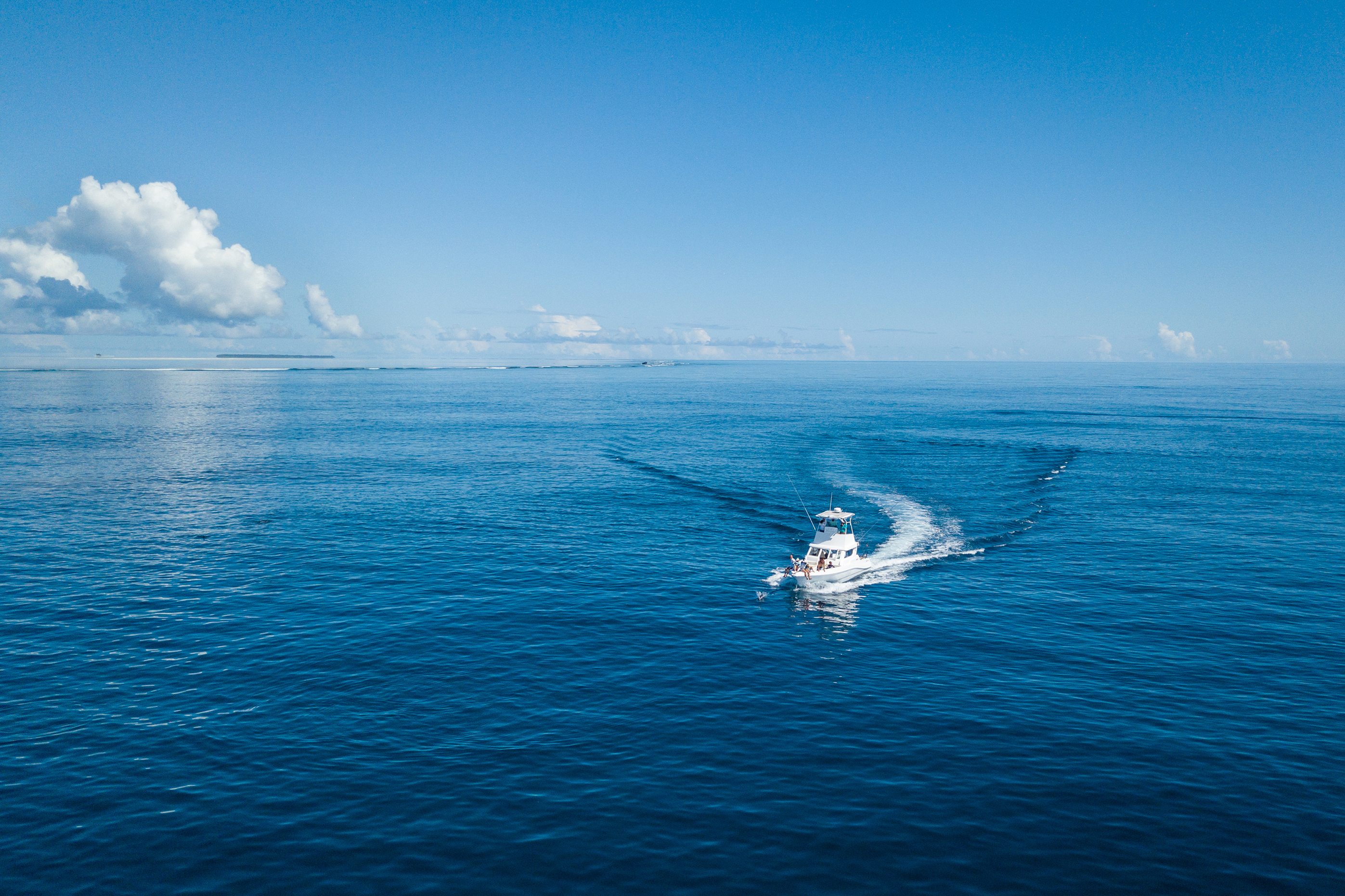 A white boat sailing across calm blue ocean under a clear sky