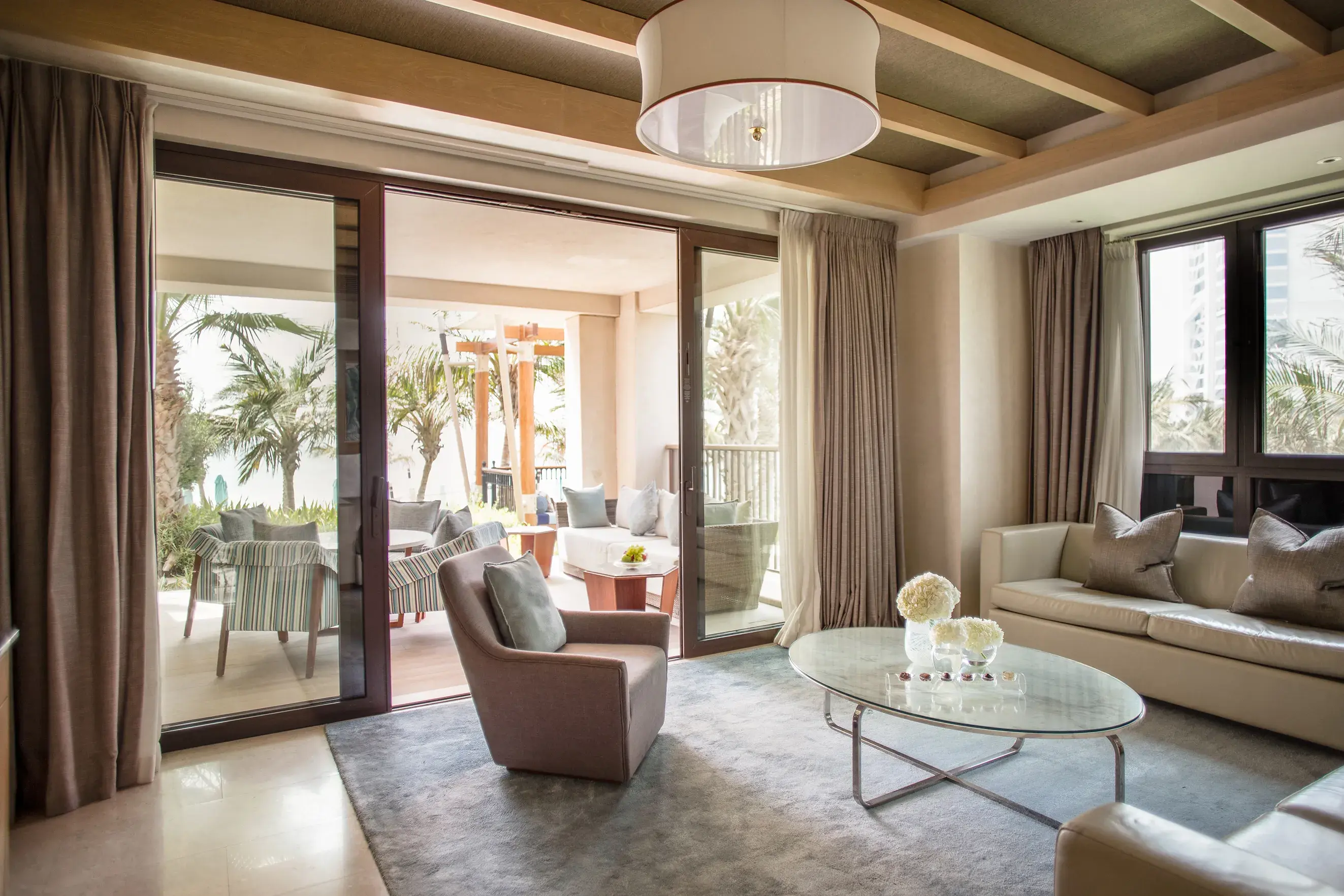 Spacious Gulf Ocean Suite living room at Jumeirah Al Naseem Dubai with elegant modern décor and a private terrace overlooking lush palm gardens.