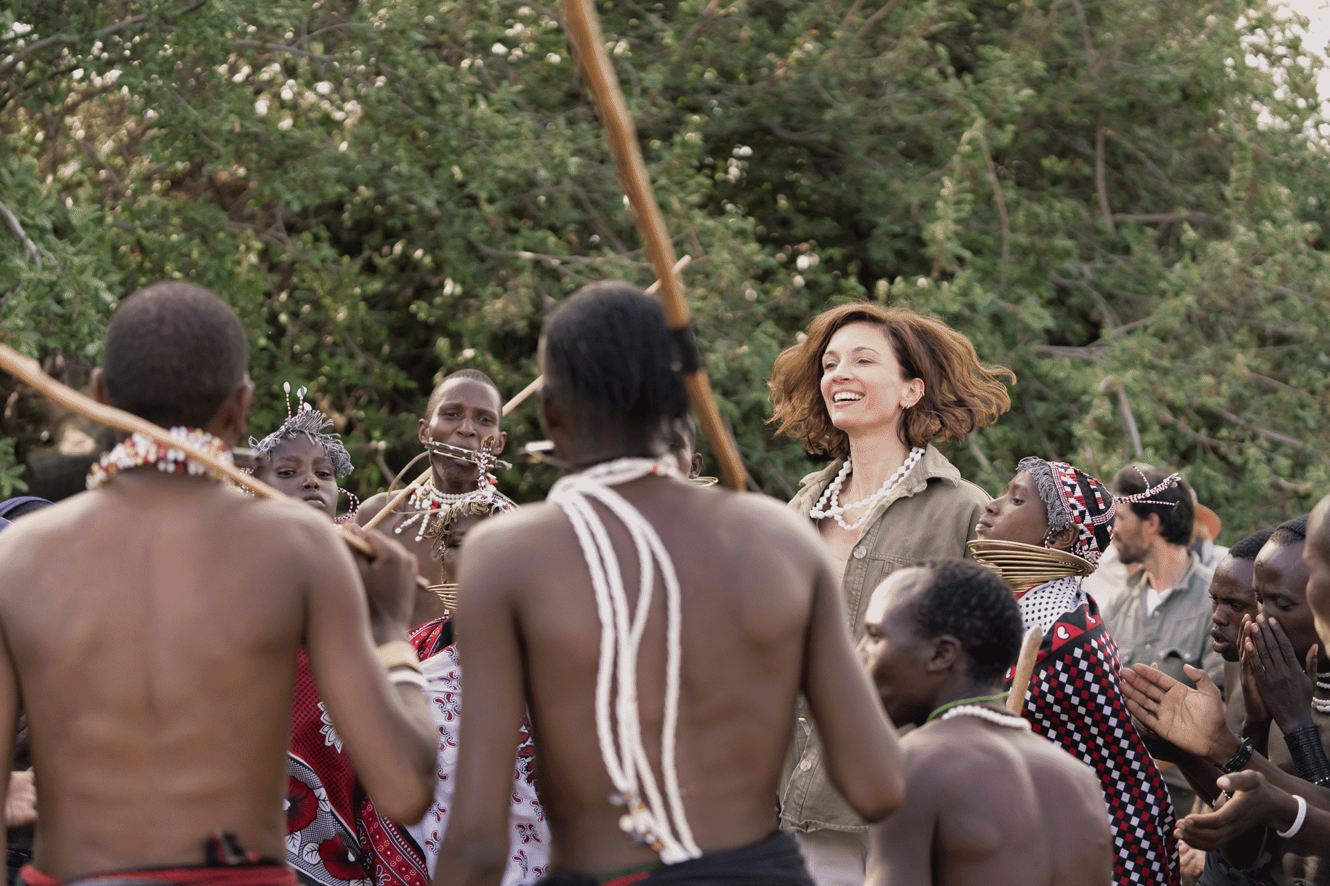 Guest participating in a traditional dance with a local community group in an outdoor natural setting.