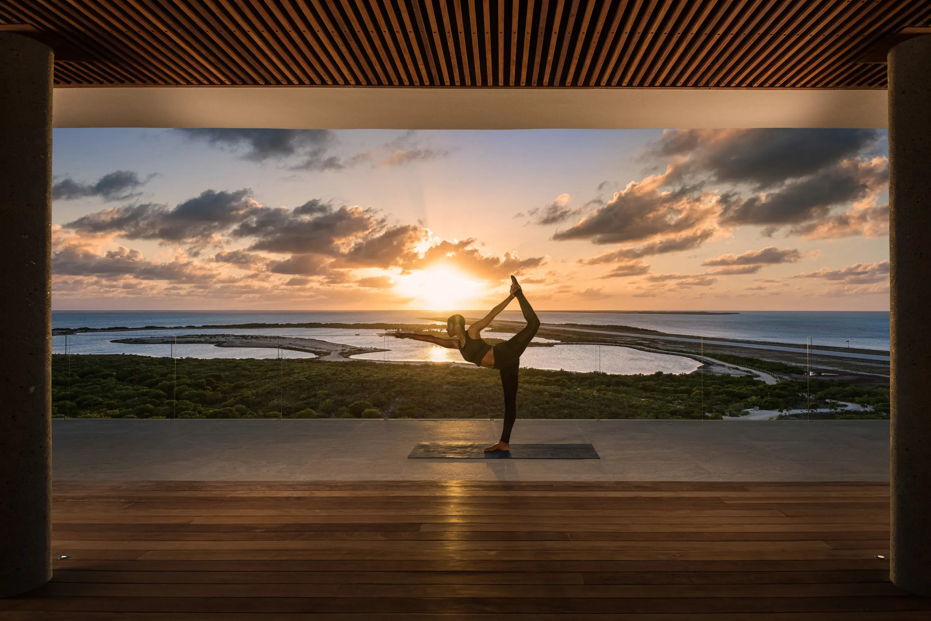 A guest practicing yoga before the sunset in the fitness pavilion at Ambergris Cay in Turks & Caicos