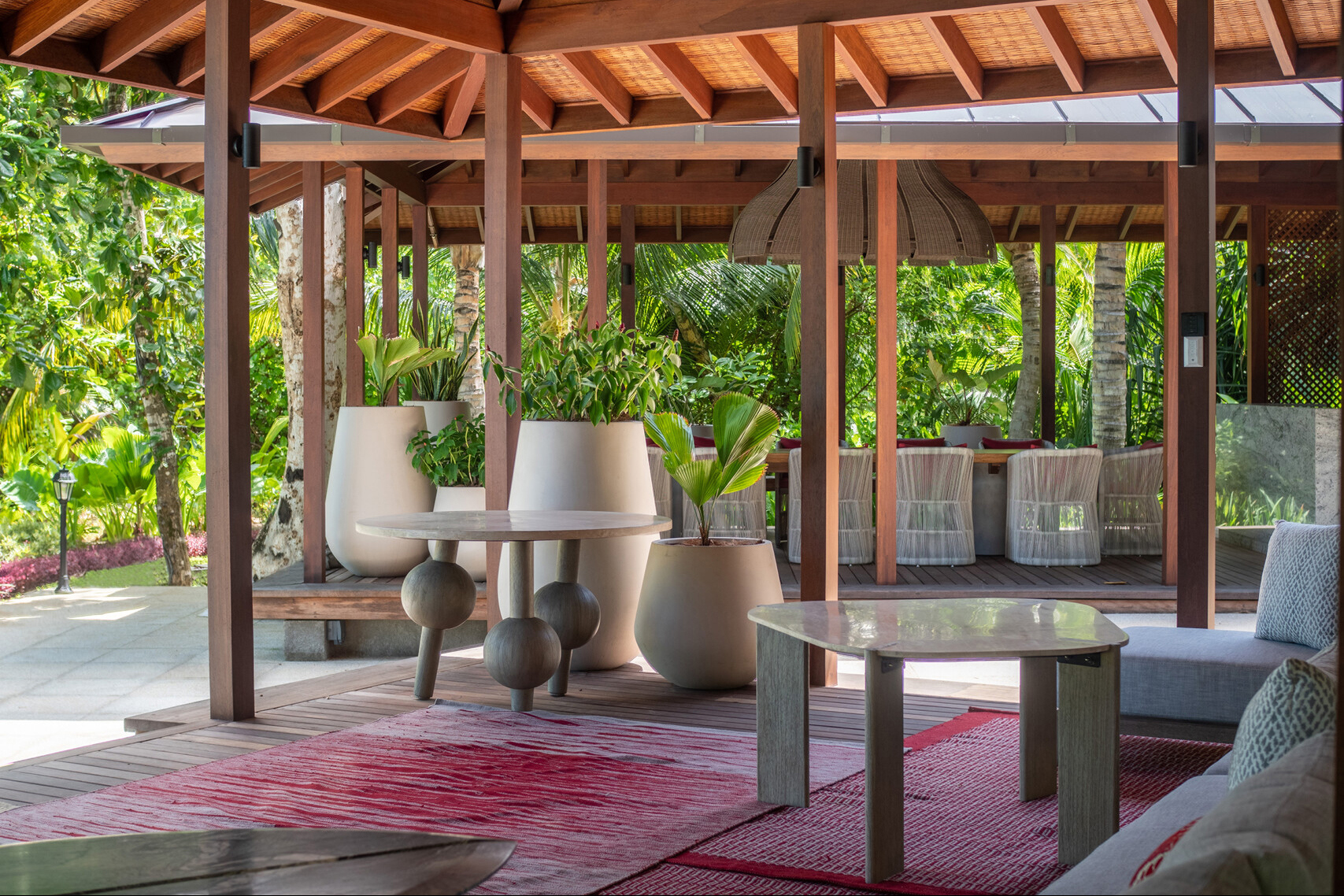 Villa seating area under wooden canopy with white chairs and vases