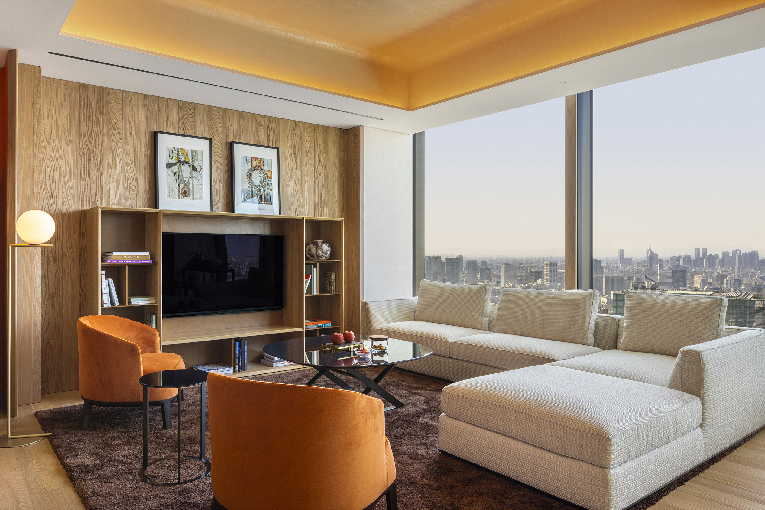 The modern lounge of a suite at Bulgari Tokyo featuring comfy sofas and a wooden television unit with large windows