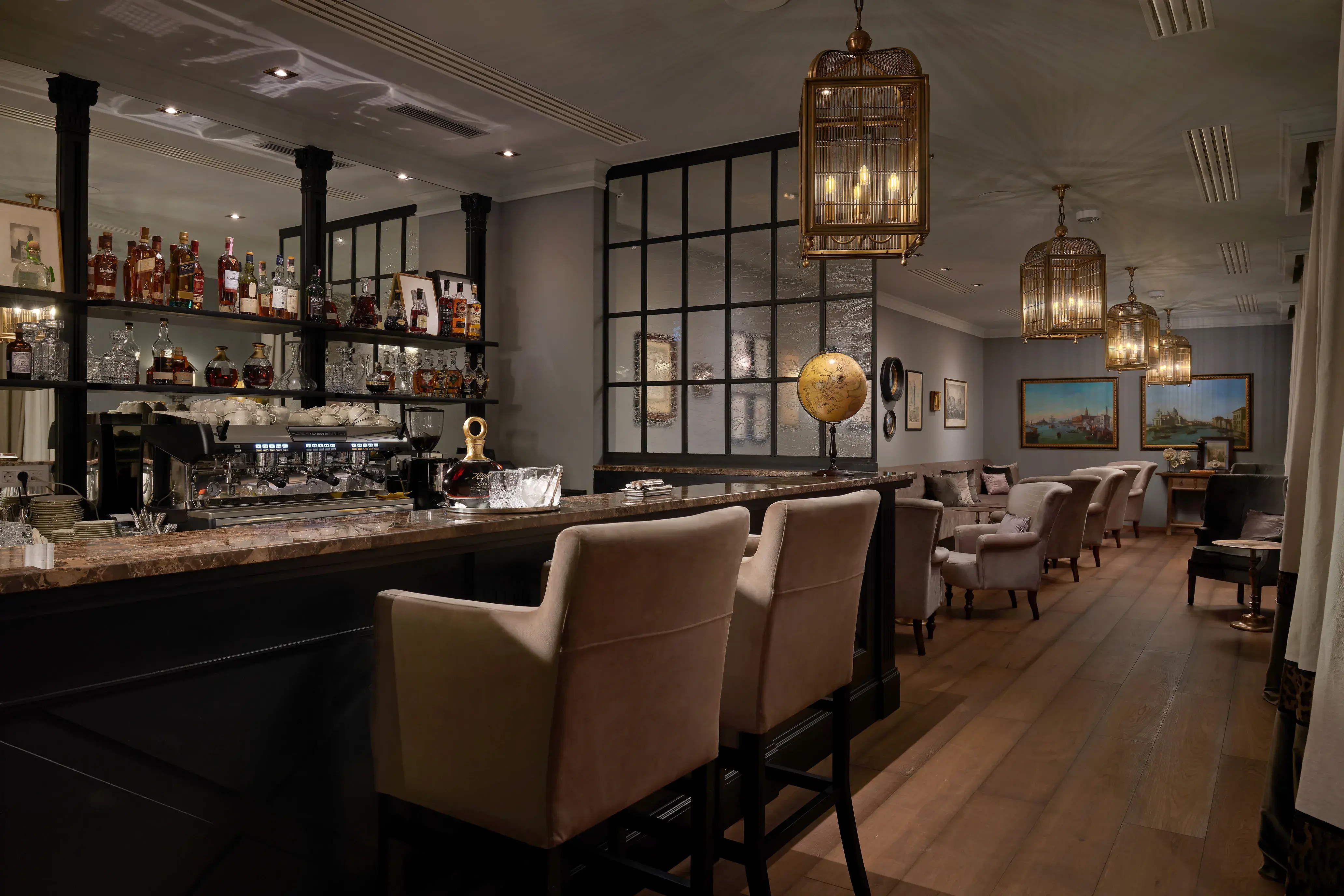 The Bar at Palace Elisabeth in Croatia featuring a well stocked bar area with high chairs leading into a comfy seating area with decorative lanterns and artwork