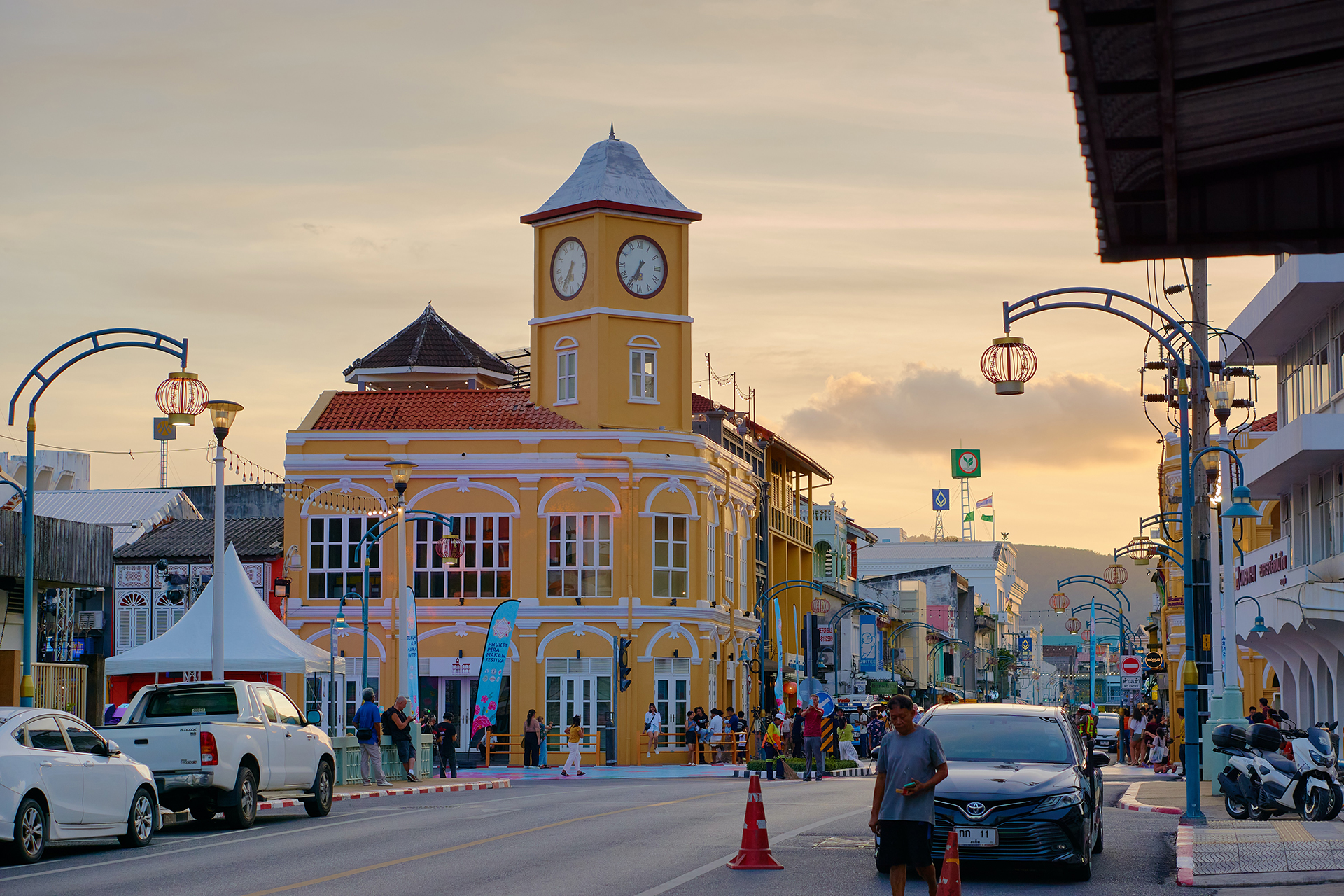 A yellow building with a clock on the top of it near a busy street
