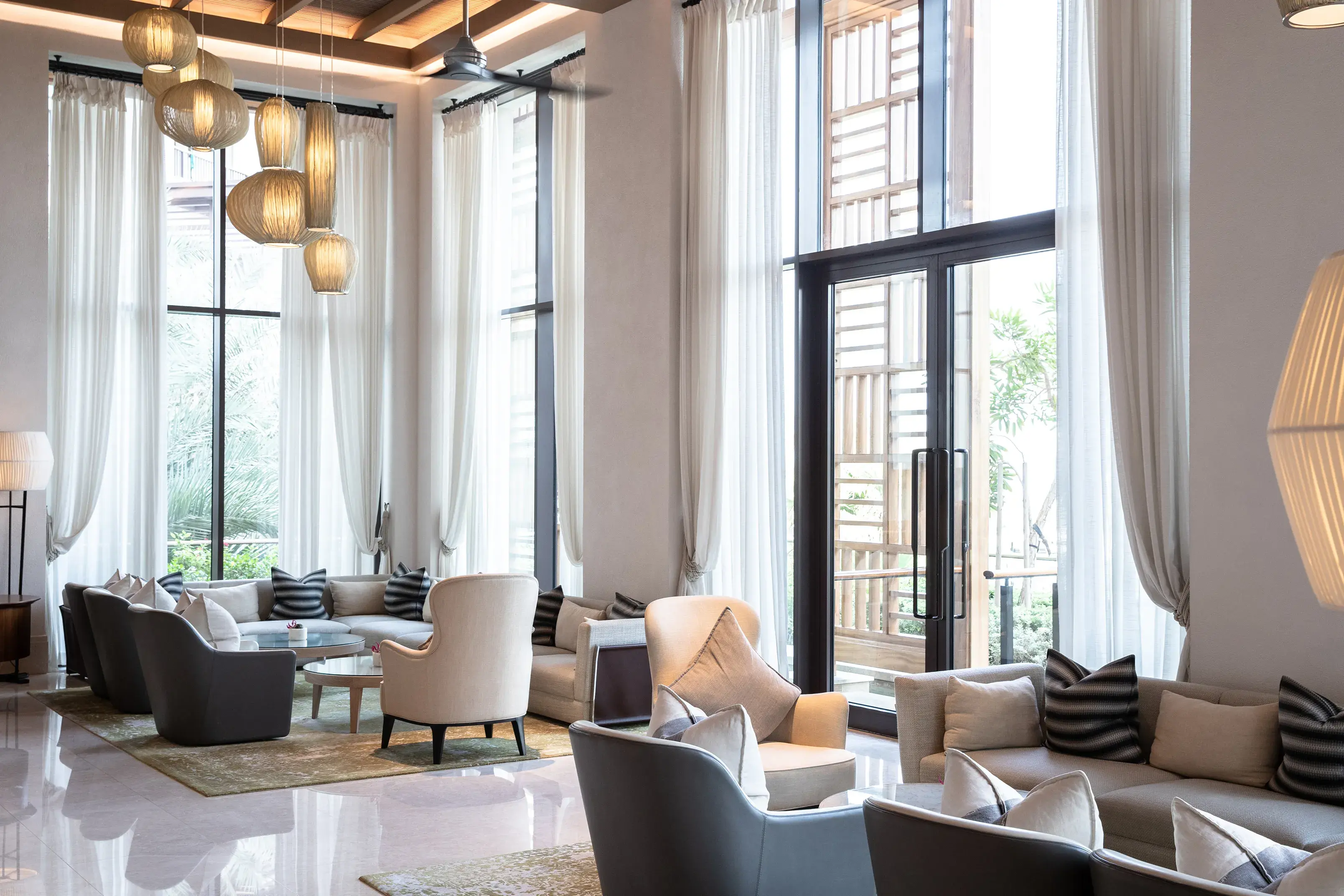 Bright contemporary lounge at Jumeirah Al Naseem Dubai featuring high ceilings, elegant seating and floor‑to‑ceiling windows.