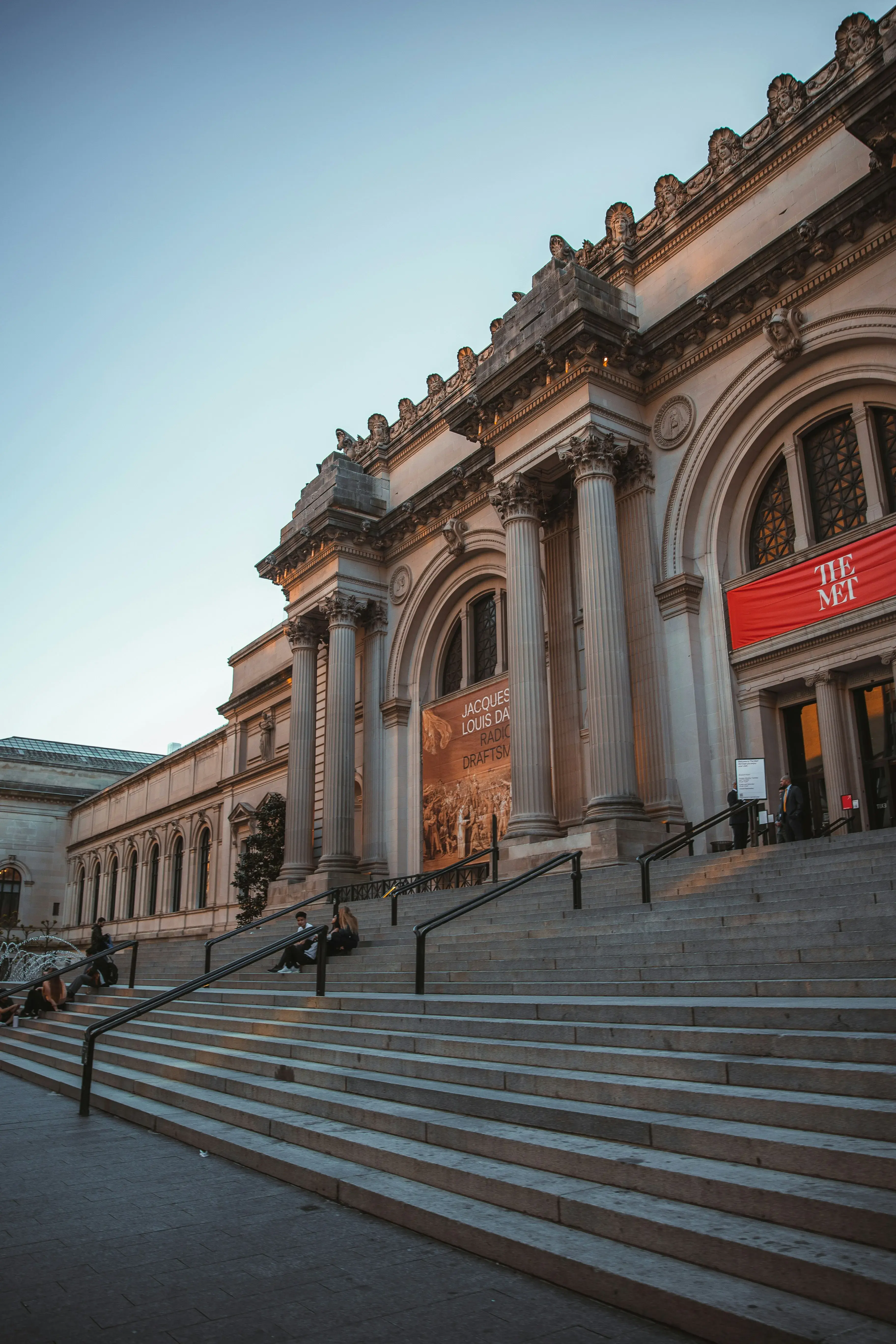 Historic facade of the Metropolitan Museum of Art in New York with ornate columns and fountain in front.