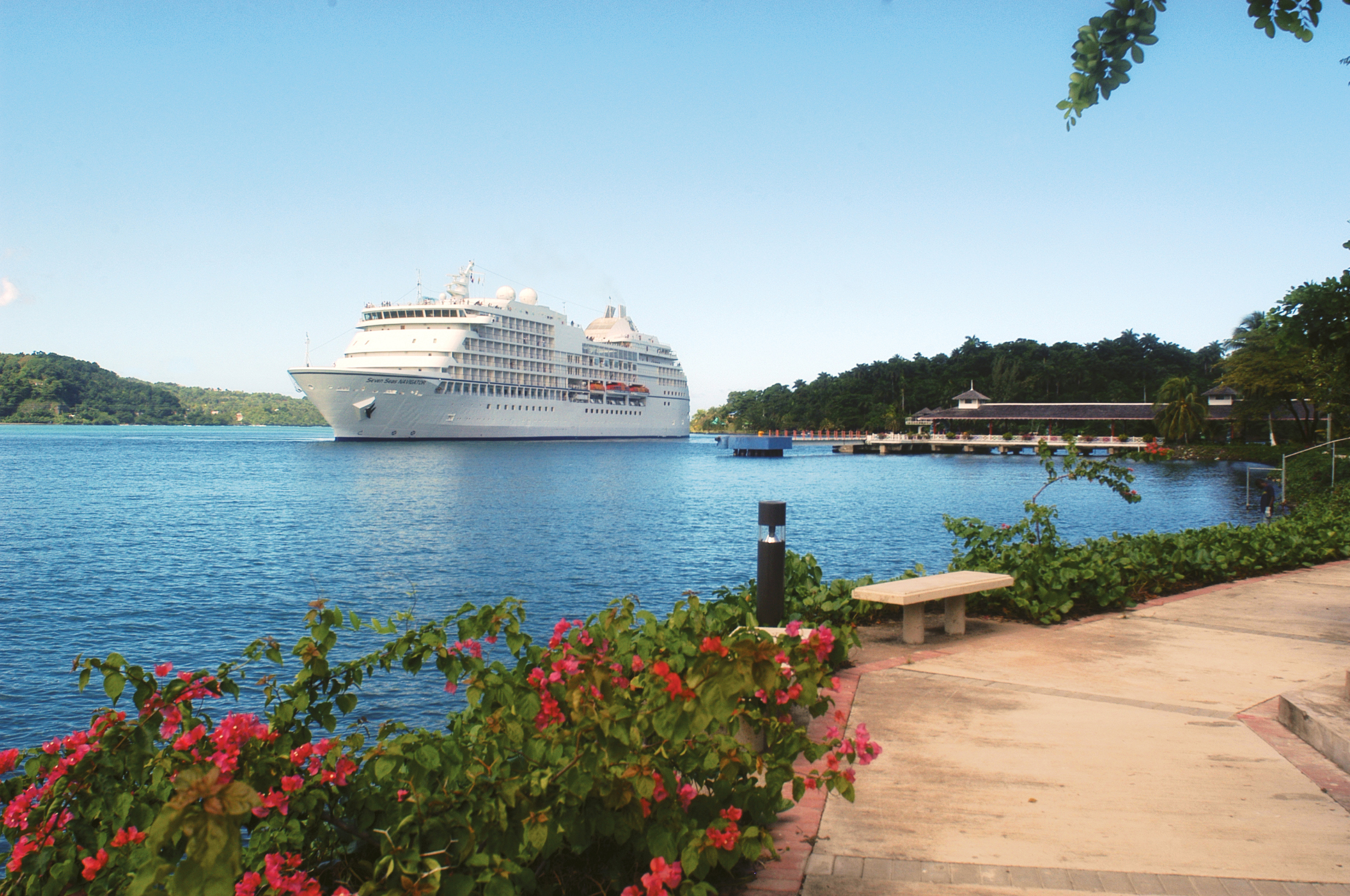 The Seven Seas Navigator luxury cruise ship at port in a harbour with blooming pink flowers
