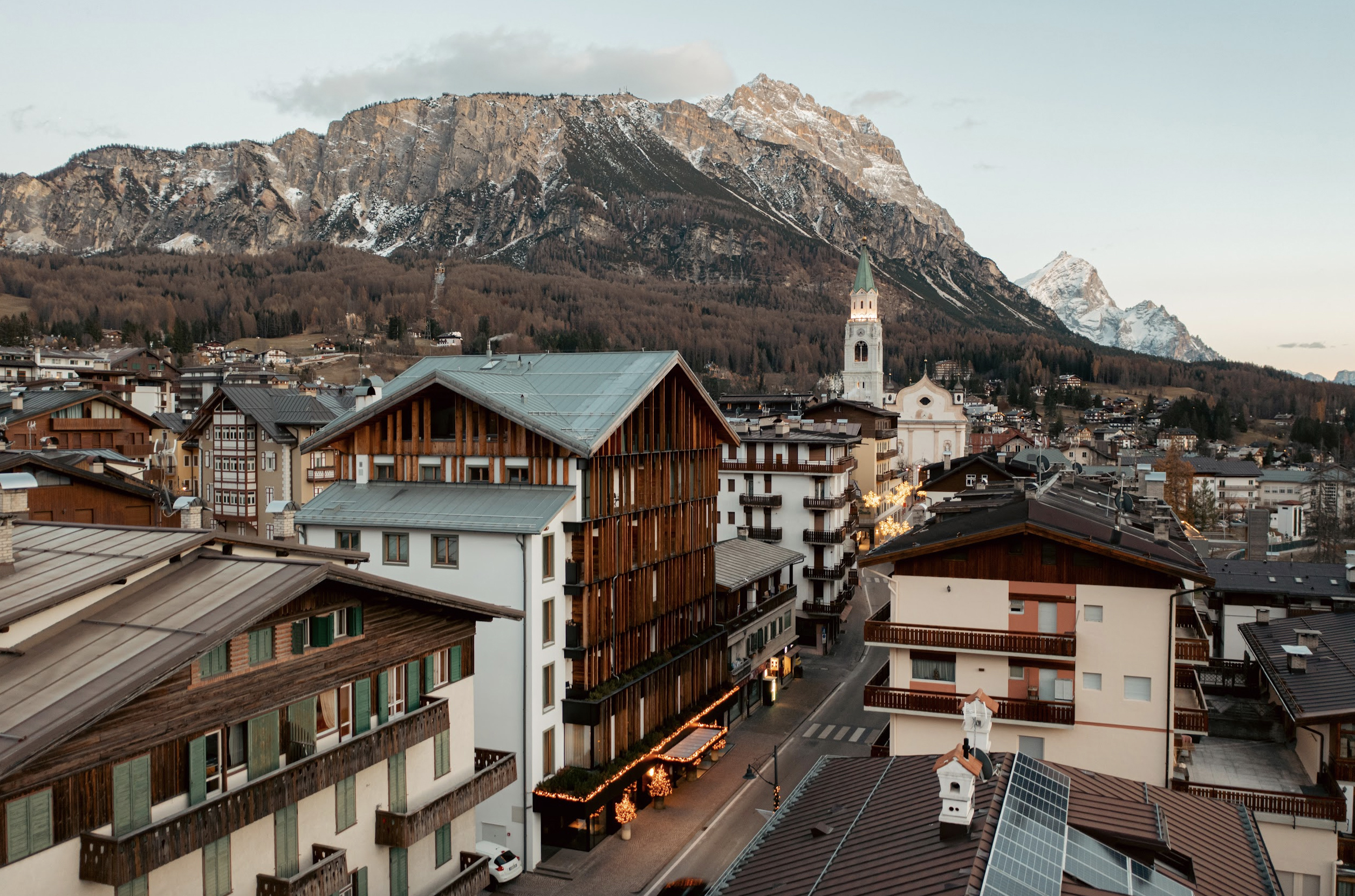 Street view of Hotel de Len exterior with town landmarks and mountains in the background