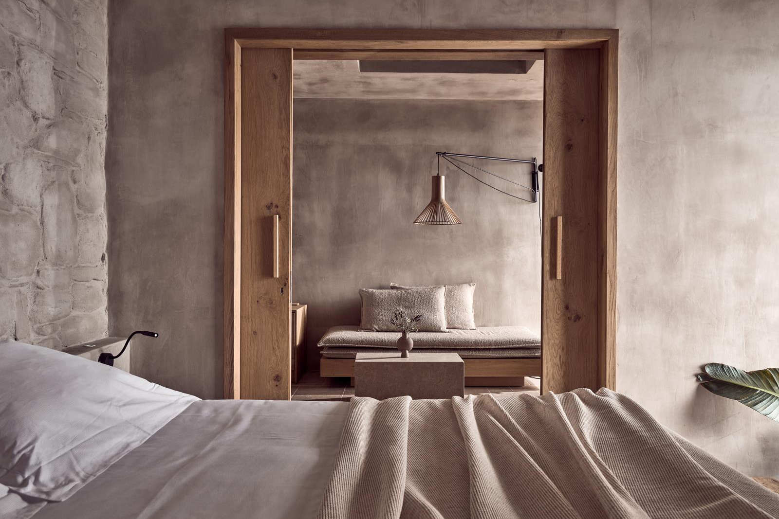 Bed with sliding doors leading to lounge area of a suite at Acro Wellness