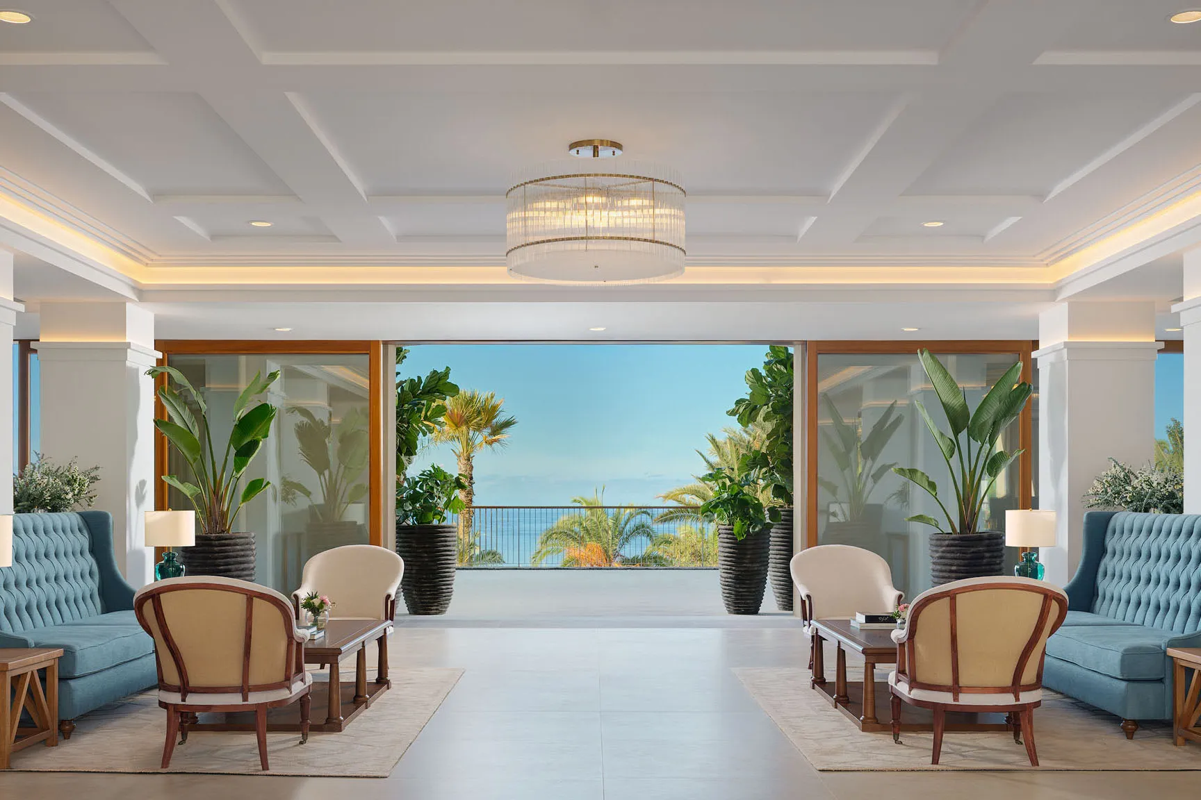 Bright and elegant lobby at Gran Hotel Taoro in Tenerife featuring chic seating areas, tropical greenery and a central chandelier.