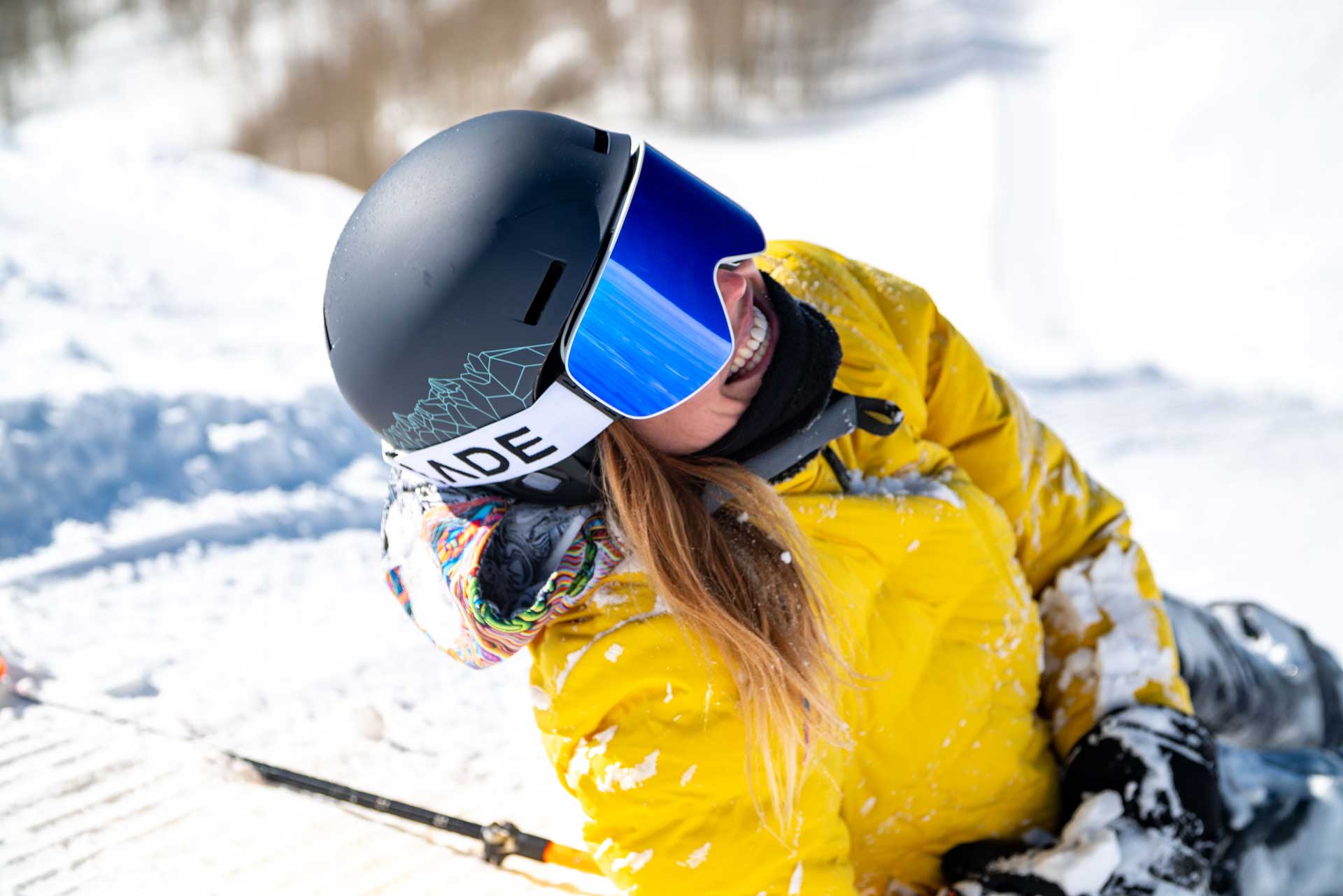 A woman wearing a yellow jacket and black helmet simling towards the camera