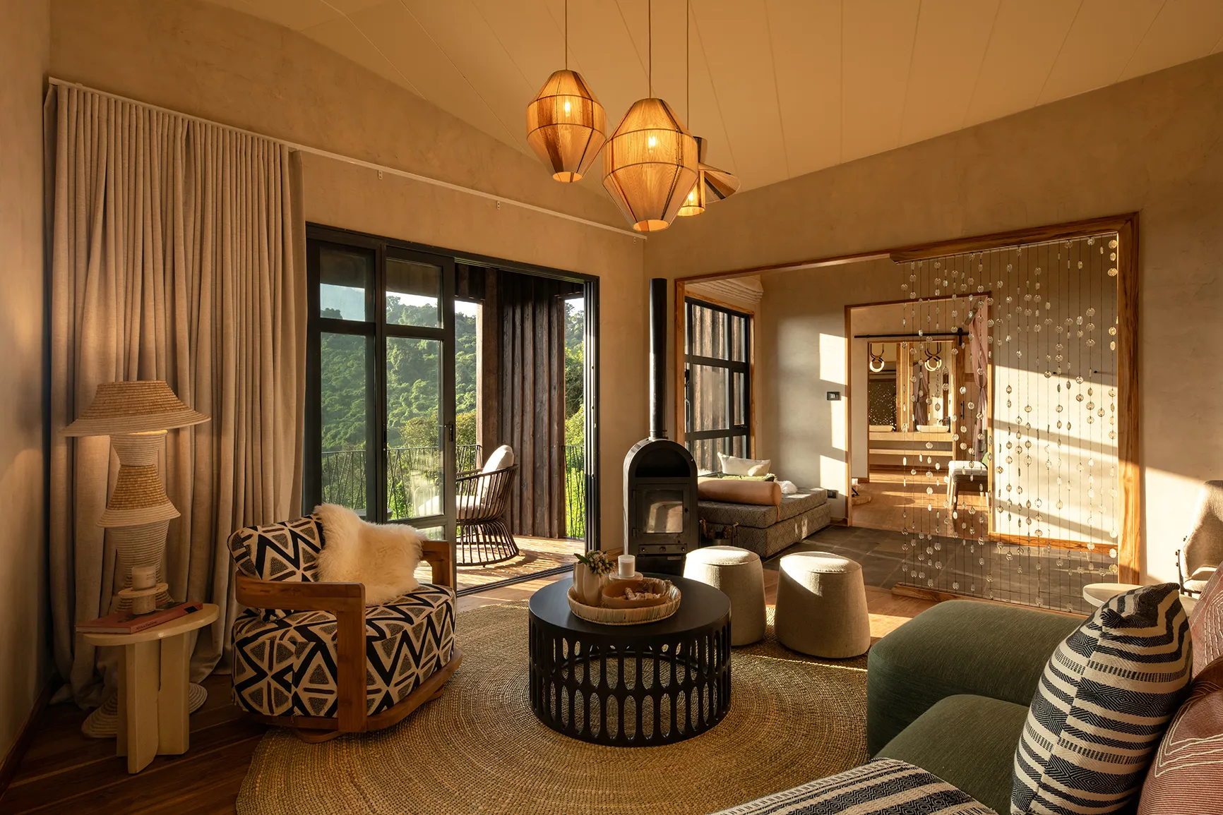 Cozy lodge suite with lounge seating, pendant lights, and forest-view balcony