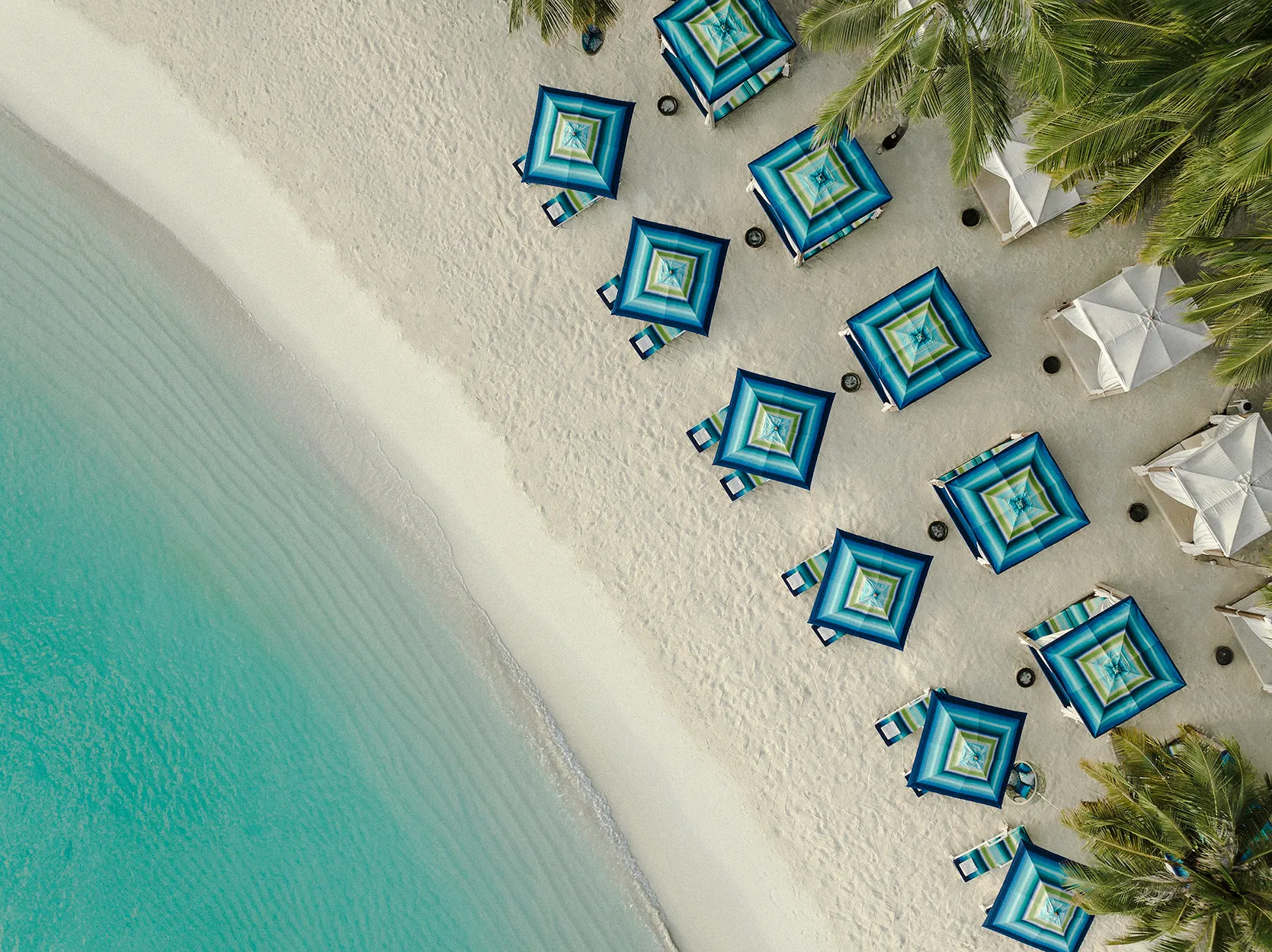 Beach and sunloungers at the beach club from above, at One&Only Reethi Rah in the Maldives