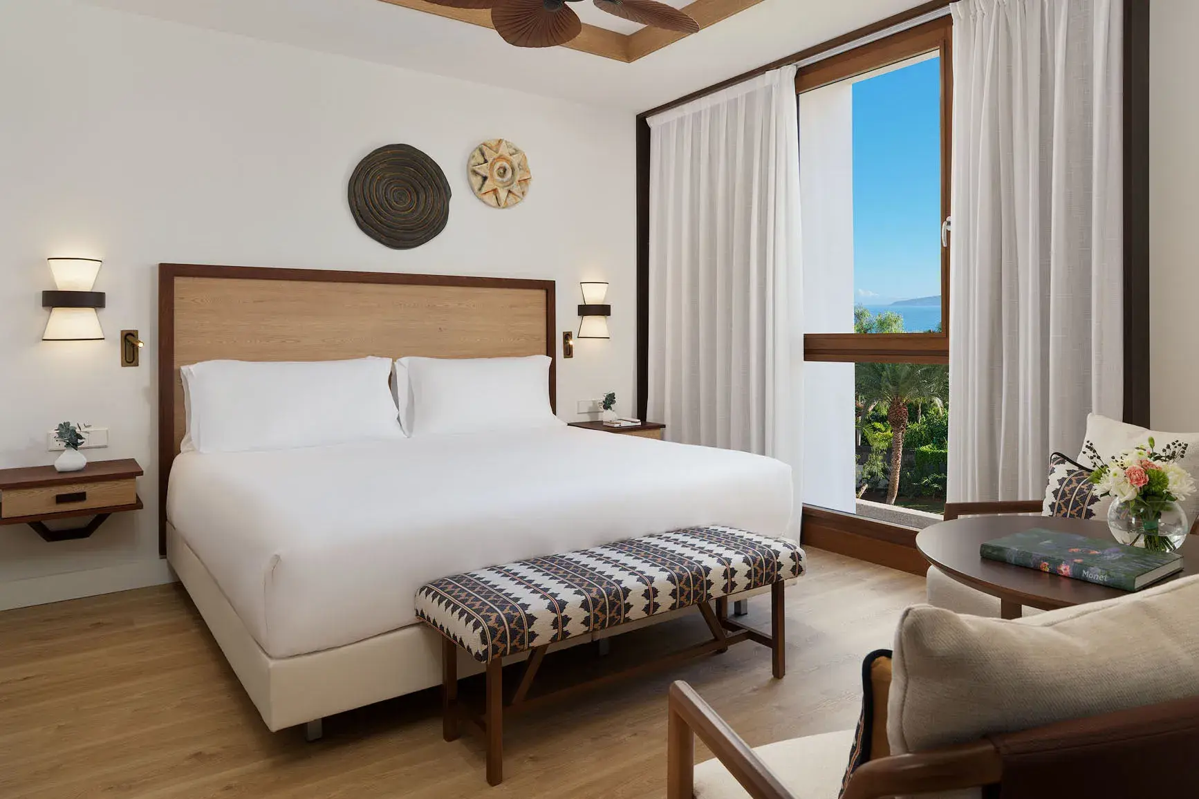 Bright deluxe room at Gran Hotel Taoro in Tenerife with modern décor and a panoramic window overlooking lush gardens and the mountains.