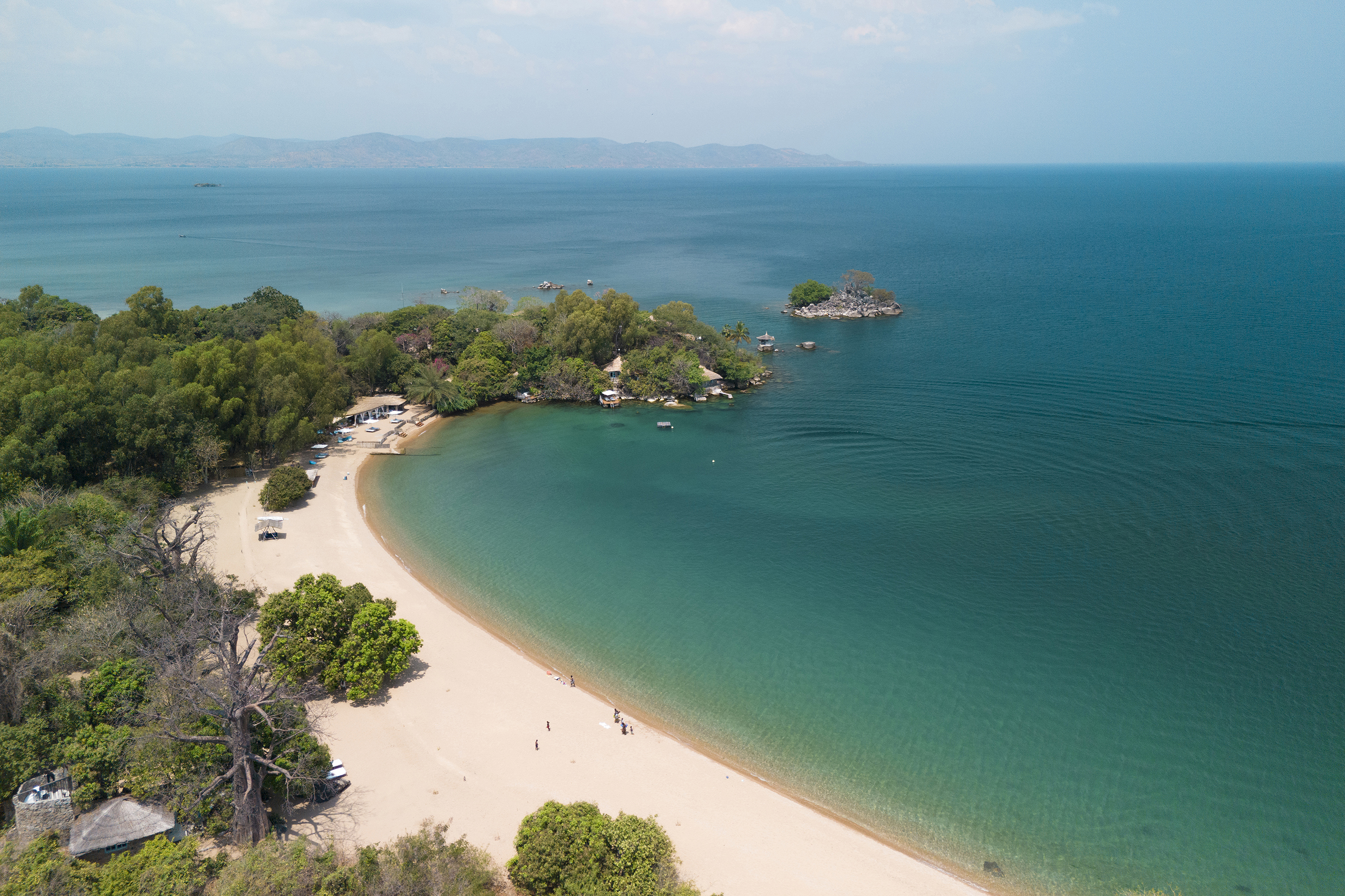 Aerial view of a pristine beach on Likoma Island with turquoise waters and lush greenery on the shoreline.
