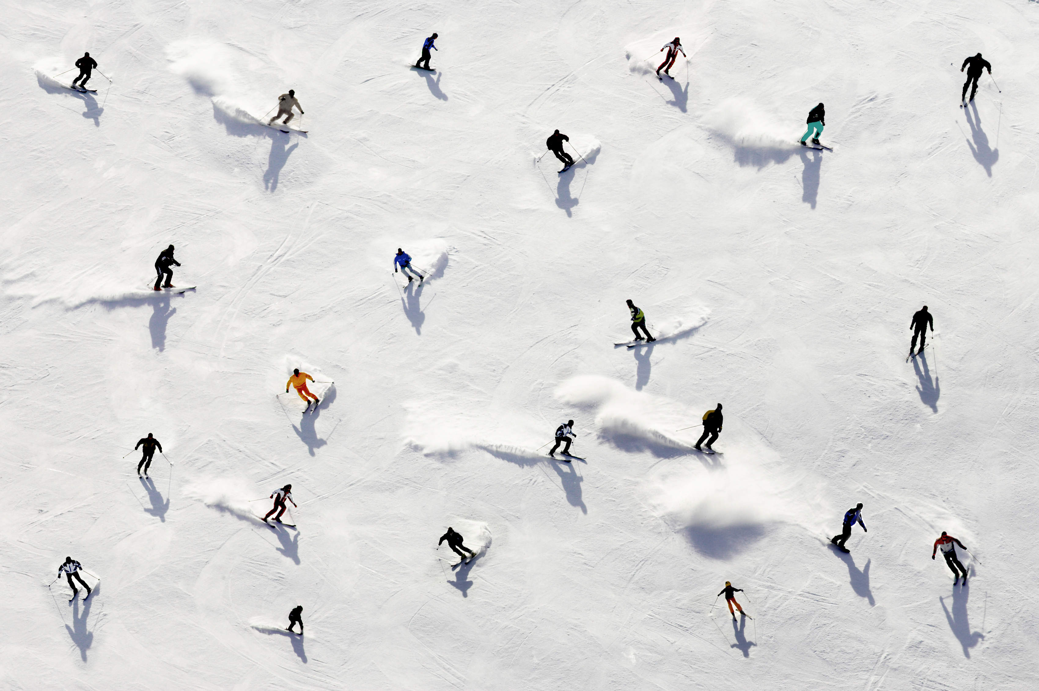 A bird's eye view of several skiers as they come down a snowy hill