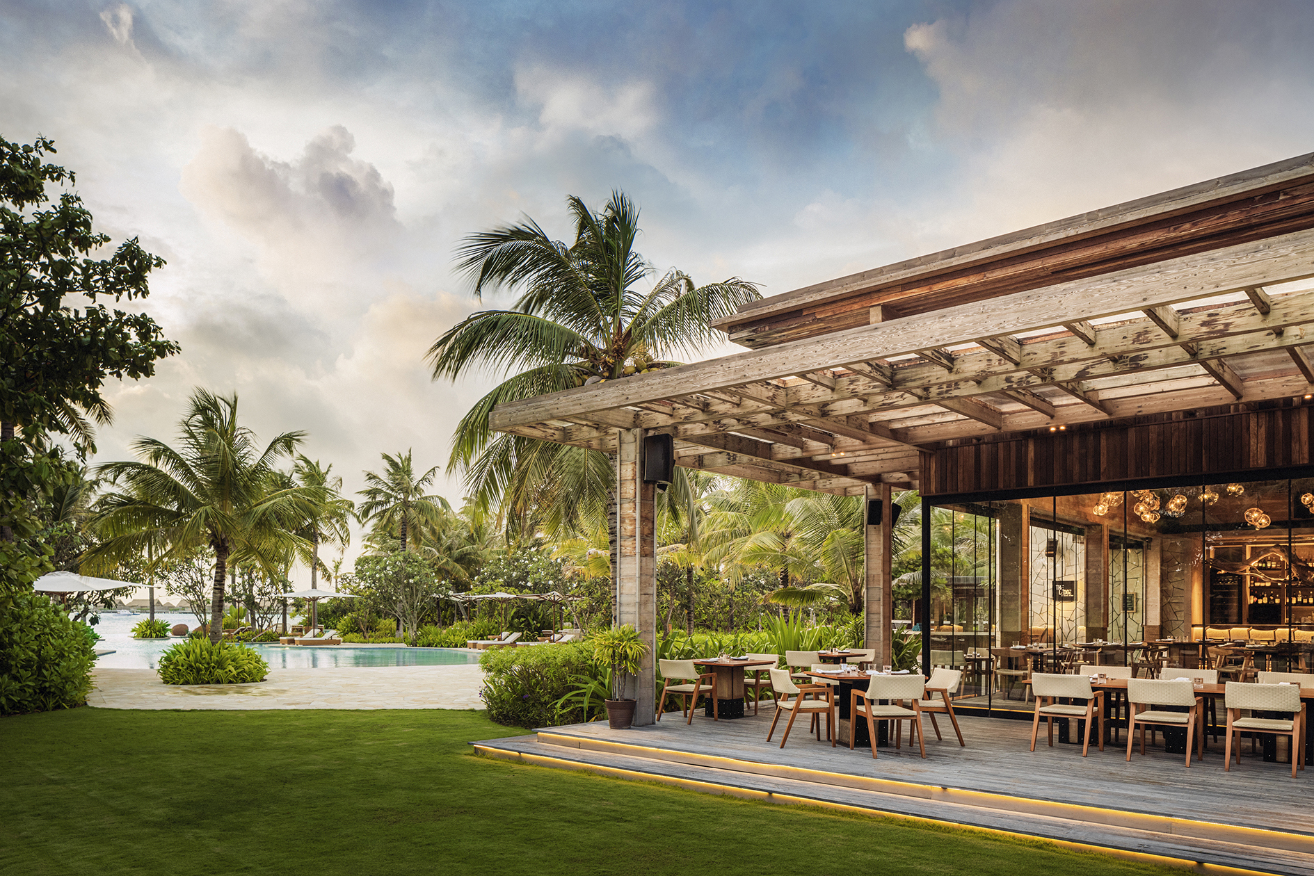 Outdoor covered terrace of The Ledge Restaurant with lagoon pool in background
