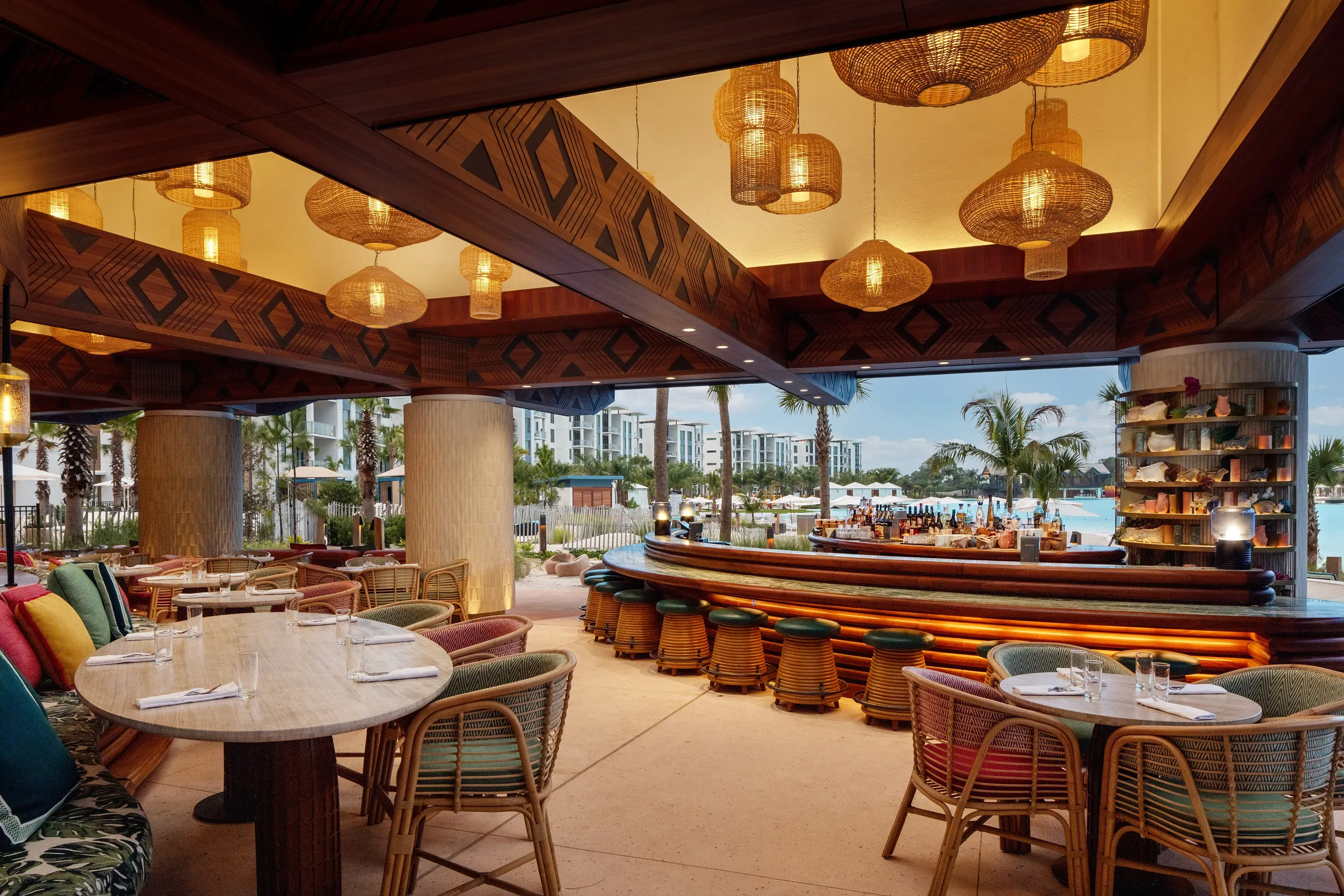 Open‑air Papaya Club restaurant and bar at Conrad Orlando in Florida featuring tropical décor, rattan seating, and views of the resort’s lagoon.