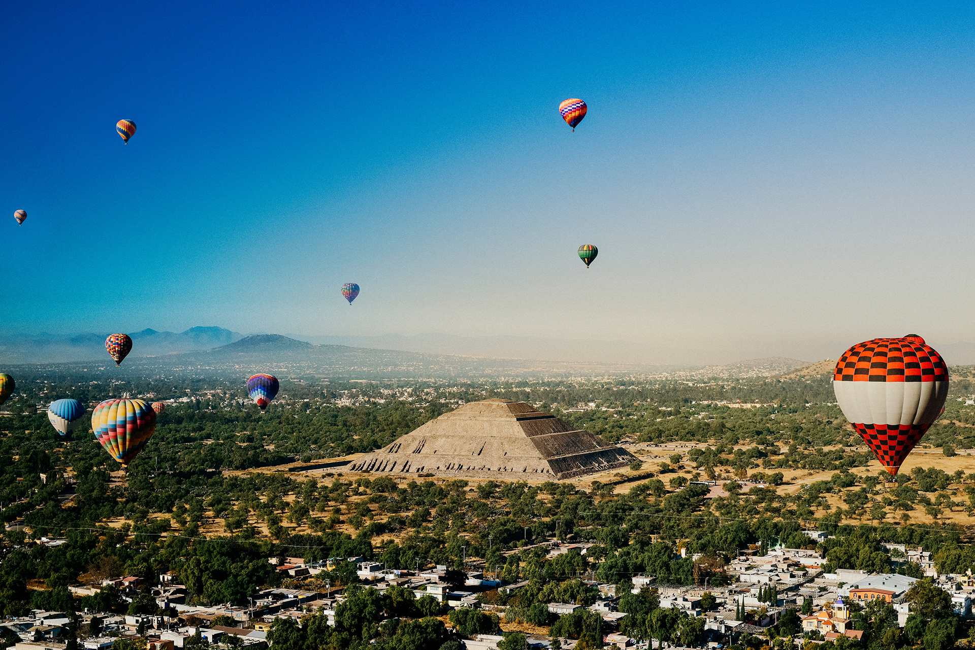 A group of hot air balloons flying over a Mexican pyramid