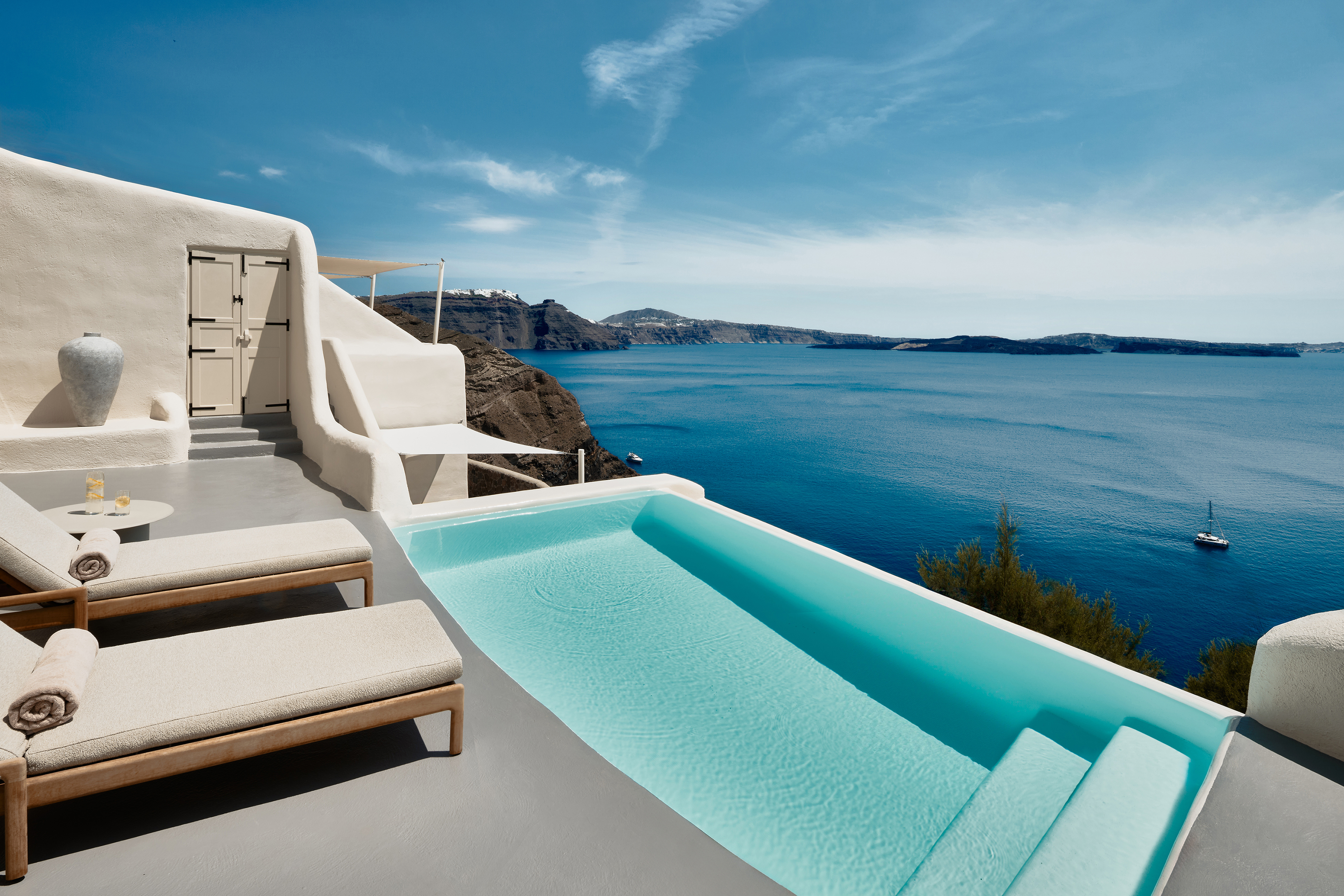 The pool terrace of a Secrecy Villa at Mystique Santorini featuring a pool and sun loungers facing the view