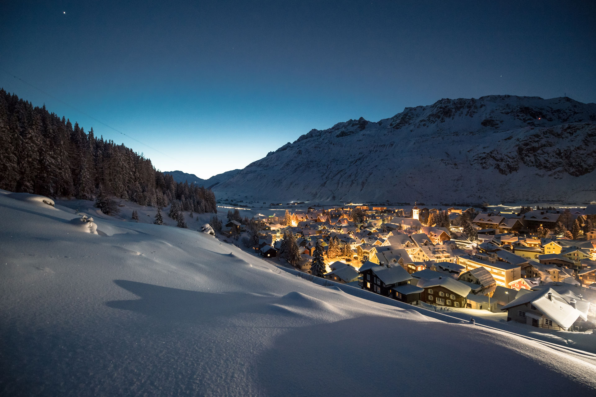 A view over the village of Andermatt that is lit up at night